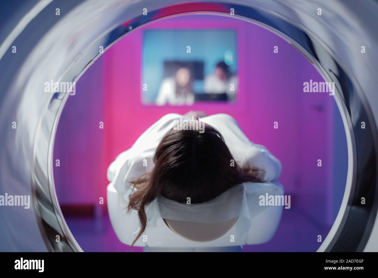 La jeune fille patient est allongé dans le tomographe et en attente d'une numérisation. Trois médecins de la salle d'examen regarder les photos Banque D'Images