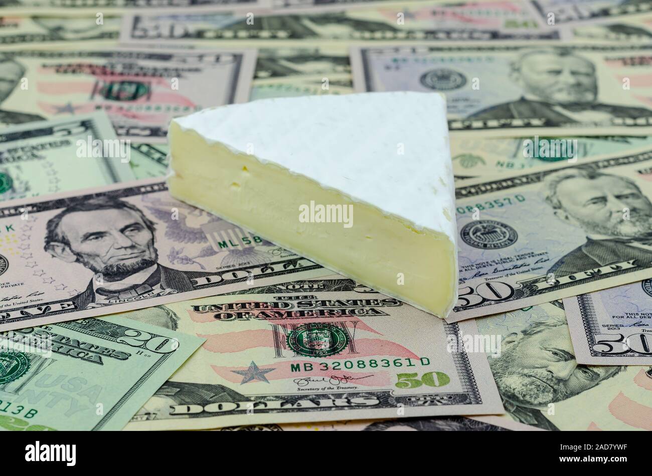 Fromage Brie française en haut de billets en dollars US. Photo conceptuelle pour nous et la France guerre commerciale et de nouveaux tarifs sur les fromages importés. Banque D'Images