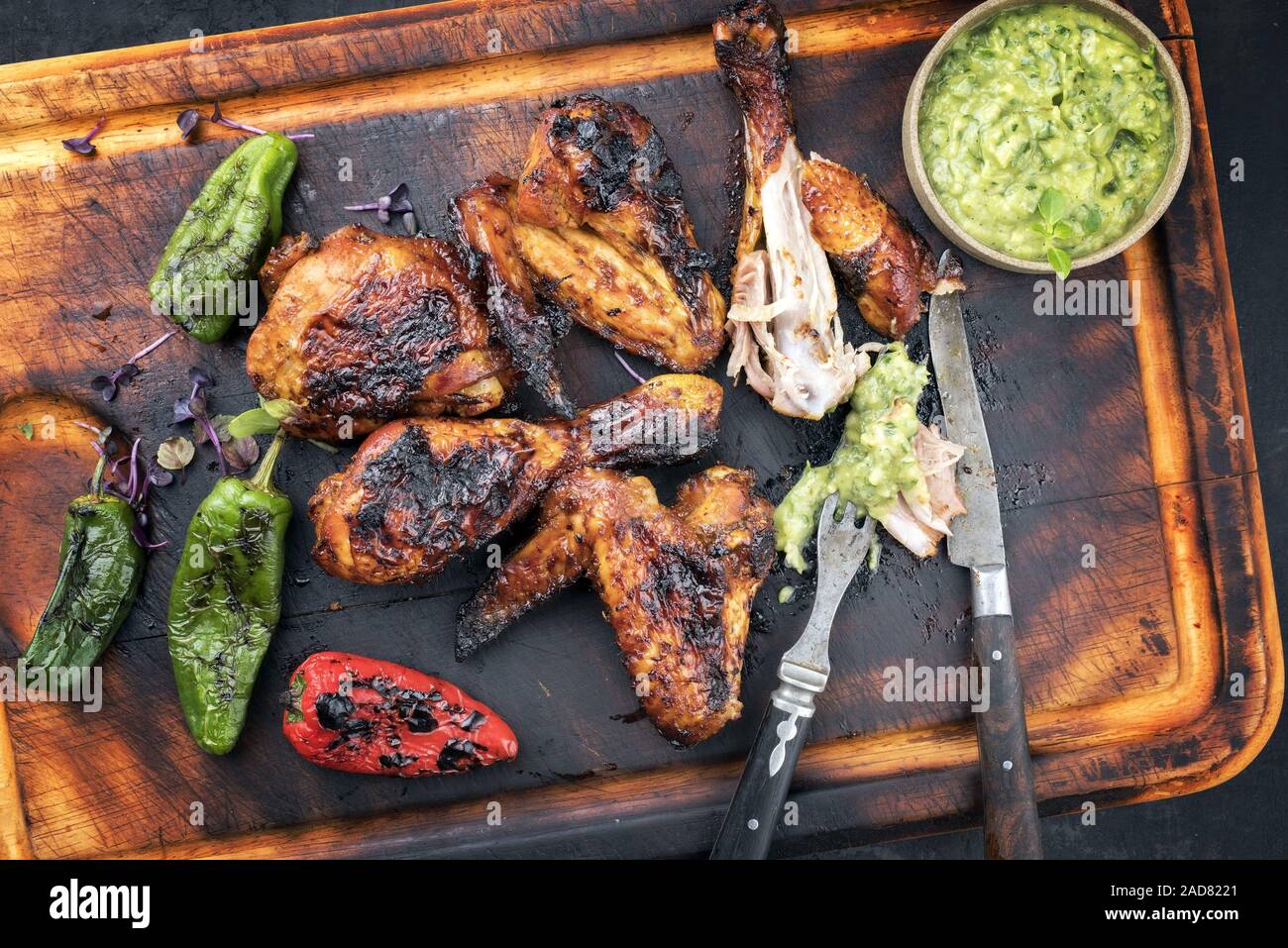 Barbecue traditionnel des Caraïbes poulet jerk ailes et pilons avec une sauce Chimichurri Banque D'Images