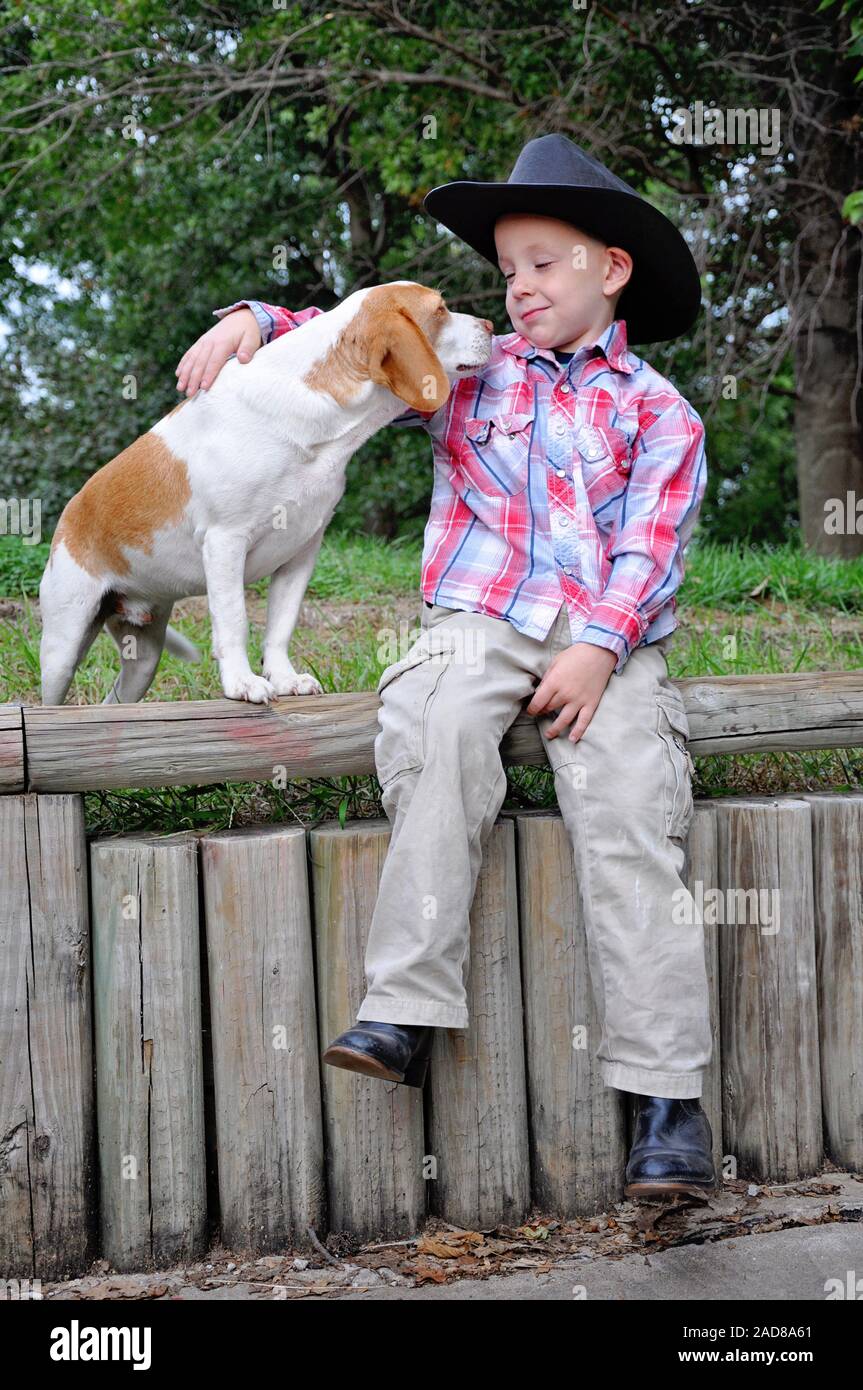 Boy wearing cowboy hat et bottes avec animal chien beagle Banque D'Images