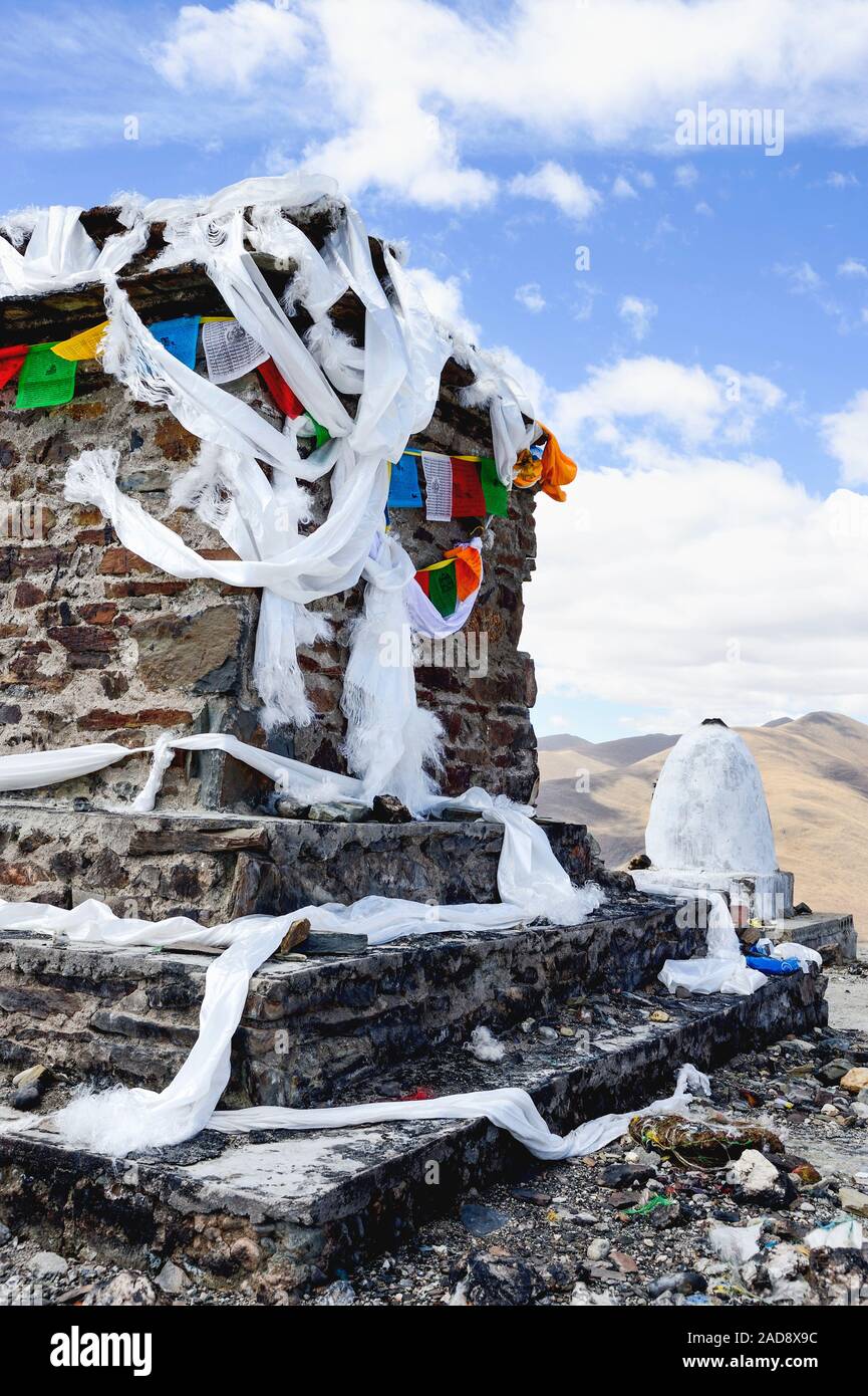 Foulards en soie blanche et les drapeaux de prières l'enrouler dans une colonne en pierre situé dans la vallée du Brahmapoutre de région autonome du Tibet, Chine. Banque D'Images