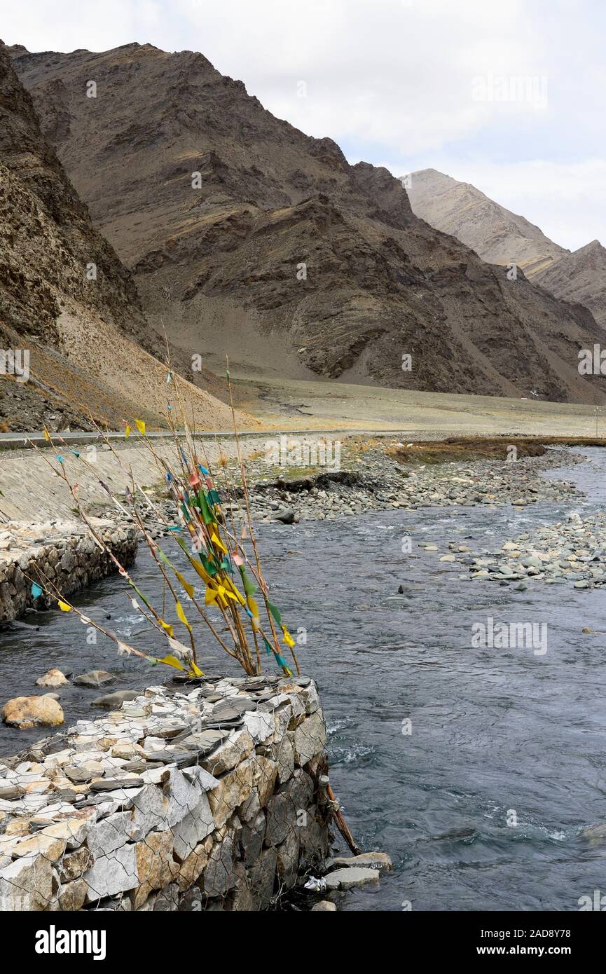 Ancrée dans le fleuve Yarlung Zangbo, Darchog les drapeaux de prières marquer la base de montagnes escarpées dans la vallée du Brahmapoutre dans la région autonome du Tibet en Chine. Banque D'Images