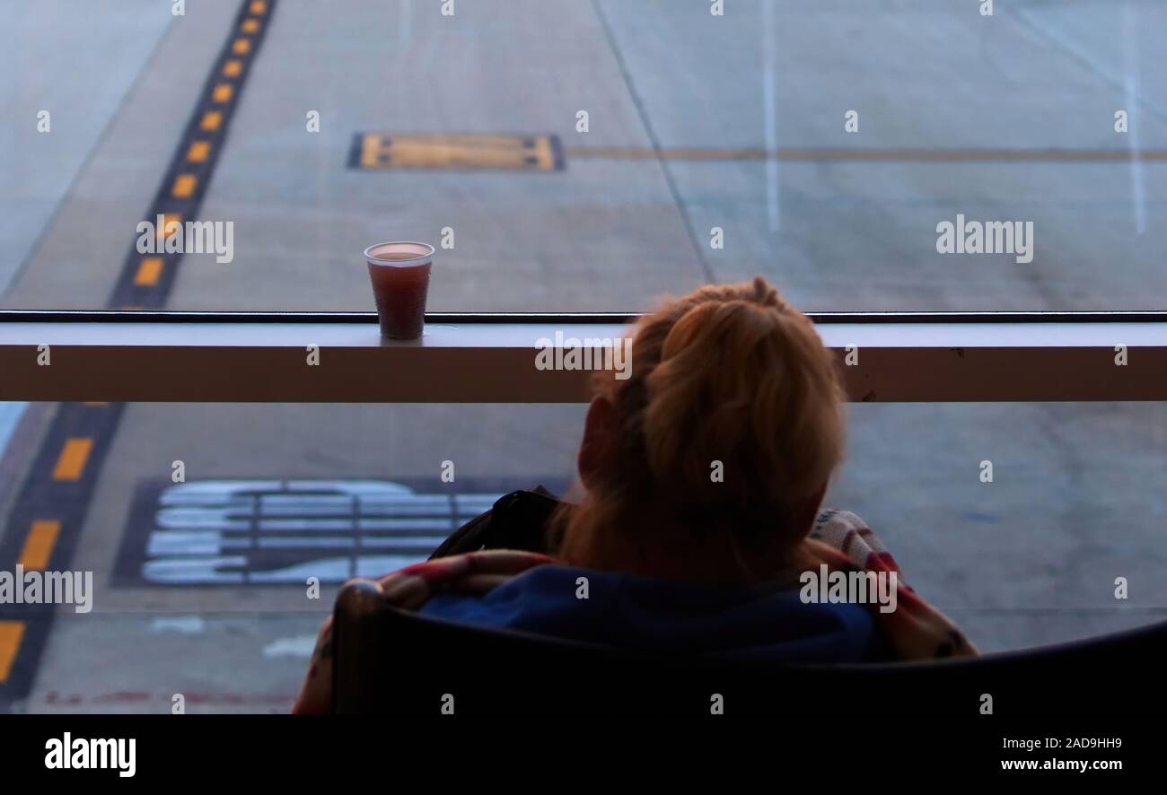 Tasse de boisson froide sans condensation sur la fenêtre terminal de l'aéroport d'un blamket dormir blotti passager. Banque D'Images