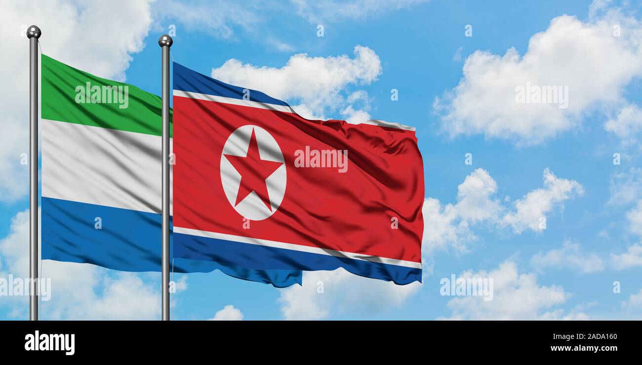 La Sierra Leone et de brandir le drapeau de la Corée du Nord dans le vent contre ciel bleu nuageux blanc ensemble. Concept de diplomatie, de relations internationales. Banque D'Images
