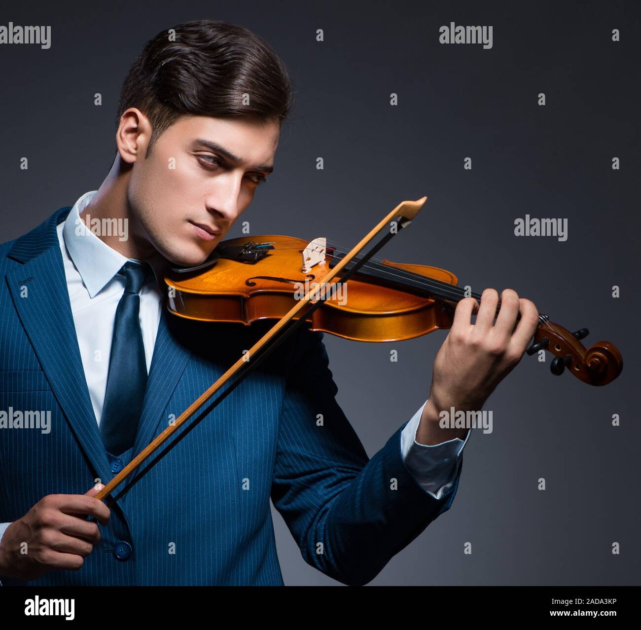 Young man playing violin in dark room Banque D'Images