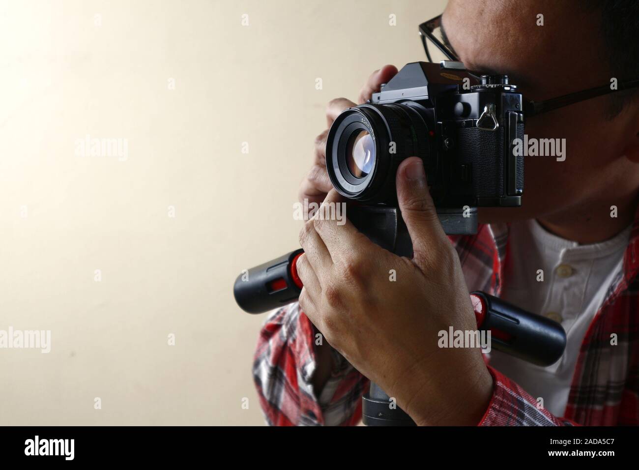 Photo d'un homme adulte détenant un vieux et petit format vintage ou 135mm sur un trépied. Banque D'Images