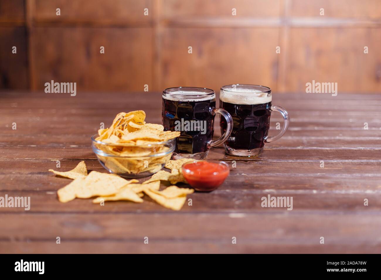 Deux chopes de bière avec des collations sur table en bois Banque D'Images