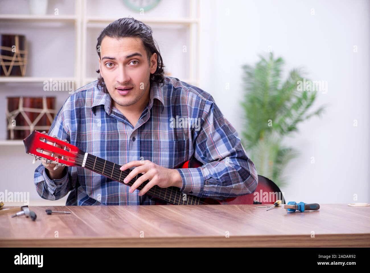 Beau jeune réparateur réparation guitare Banque D'Images