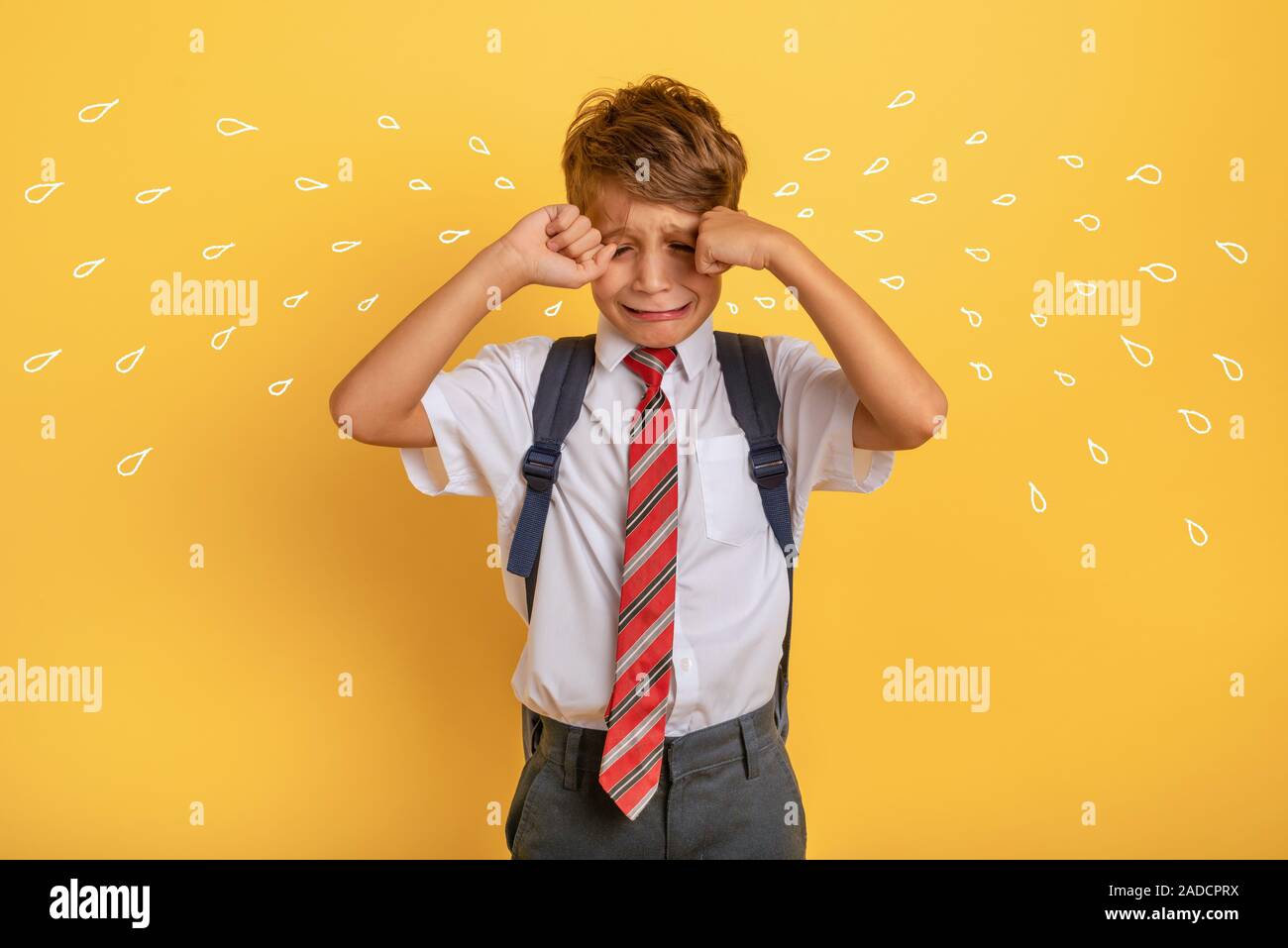 L'enfant pleure parce que ne veut pas aller à l'école. Fond jaune Banque D'Images