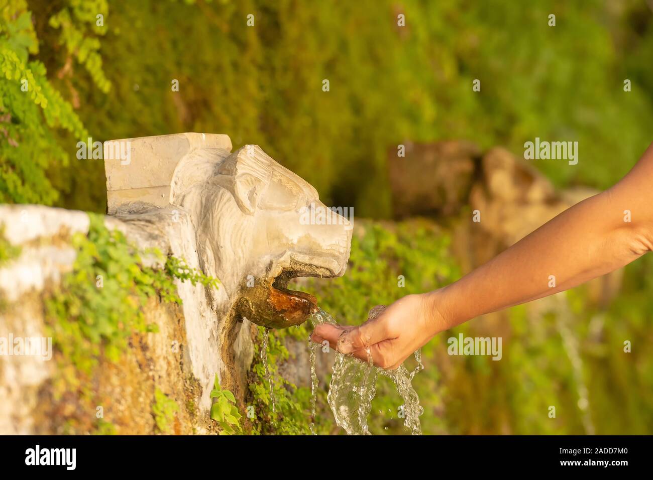 Fontaine à Andros island Menites en Grèce, avec une femme tenant un peu d'eau avec sa main. Banque D'Images