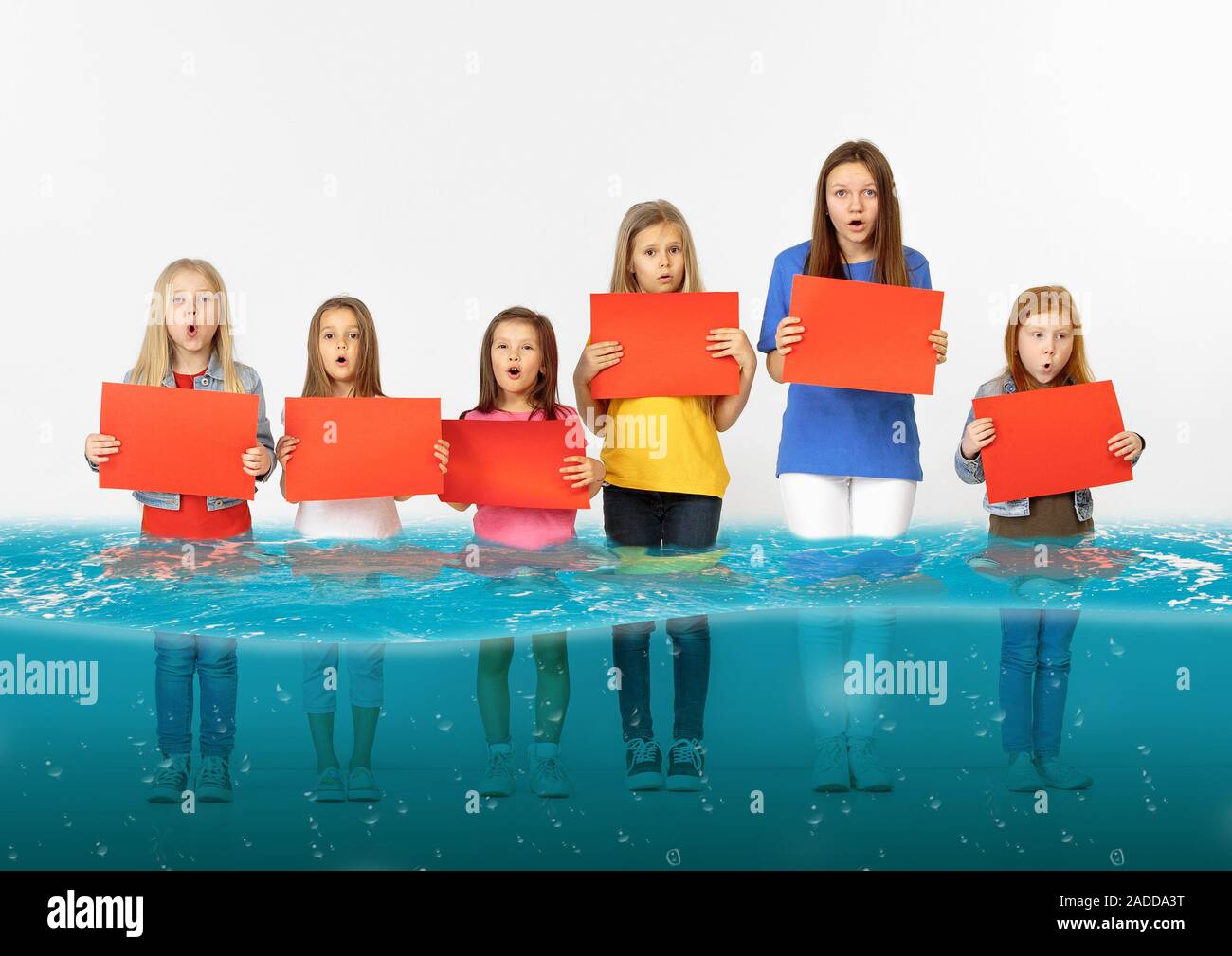 Noyé à la maison. Groupe d'enfants avec des bannières vierge debout dans l'eau de la fonte des glaciers, le réchauffement climatique. L'écologie, de l'environnement concept. Sauver la planète pour les générations futures, arrêter de dénaturer la nature. Banque D'Images