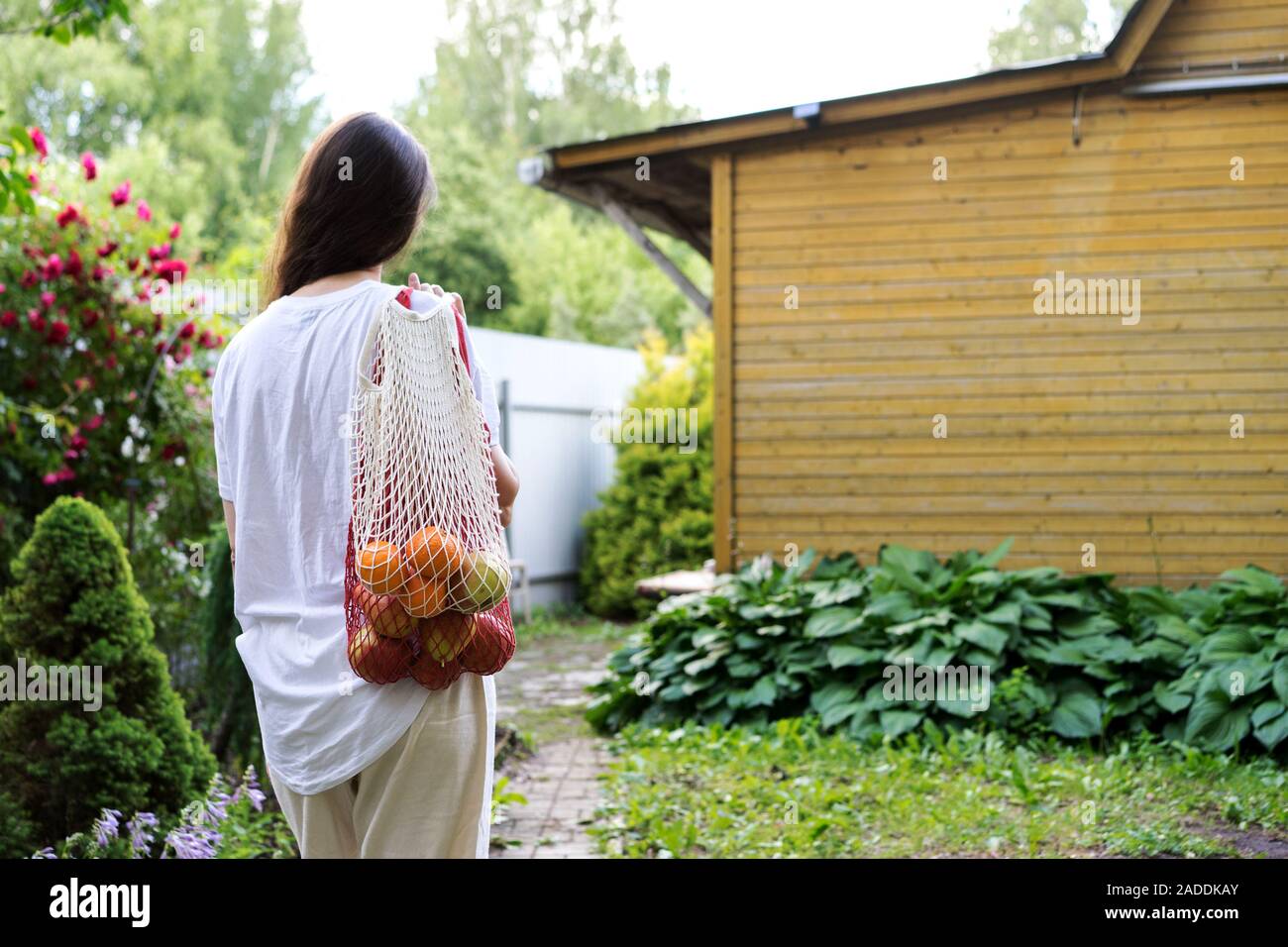 Une femme debout avec deux sacs en coton avec des pommes et des oranges Banque D'Images