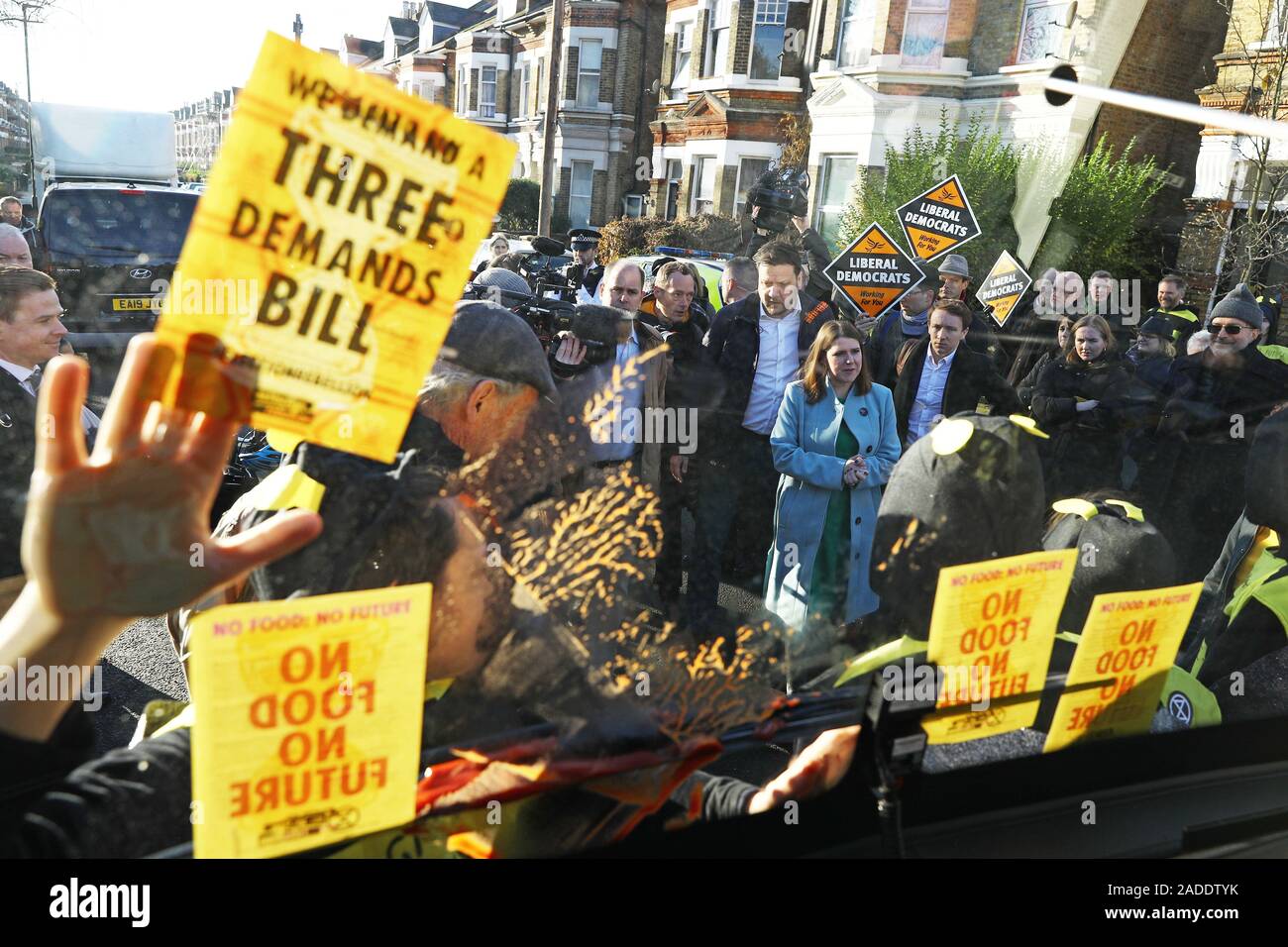 Le leader libéral démocrate Jo Swinson parle à l'extinction des manifestants déguisés en abeilles rébellion après qu'ils se sont collés à la partie bus bataille au cours d'une visite à l'établissement Knights Youth Centre à Londres, tandis que sur la campagne électorale générale trail. Banque D'Images