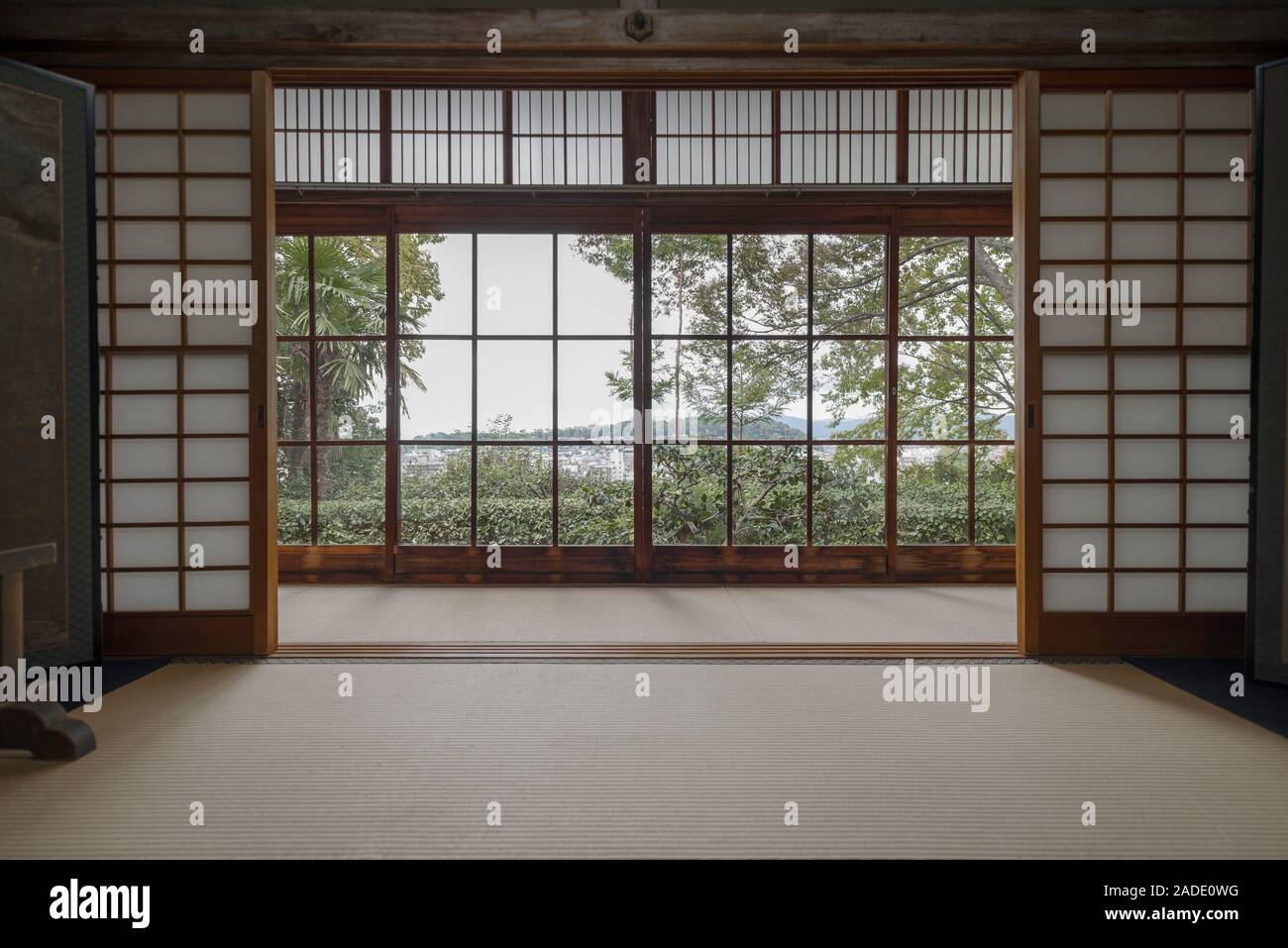Voir d'arbres verts et de Kyoto à partir d'une fenêtre dans une chambre traditionnelle avec des diviseurs de shoji et tatami à Honen-in Banque D'Images