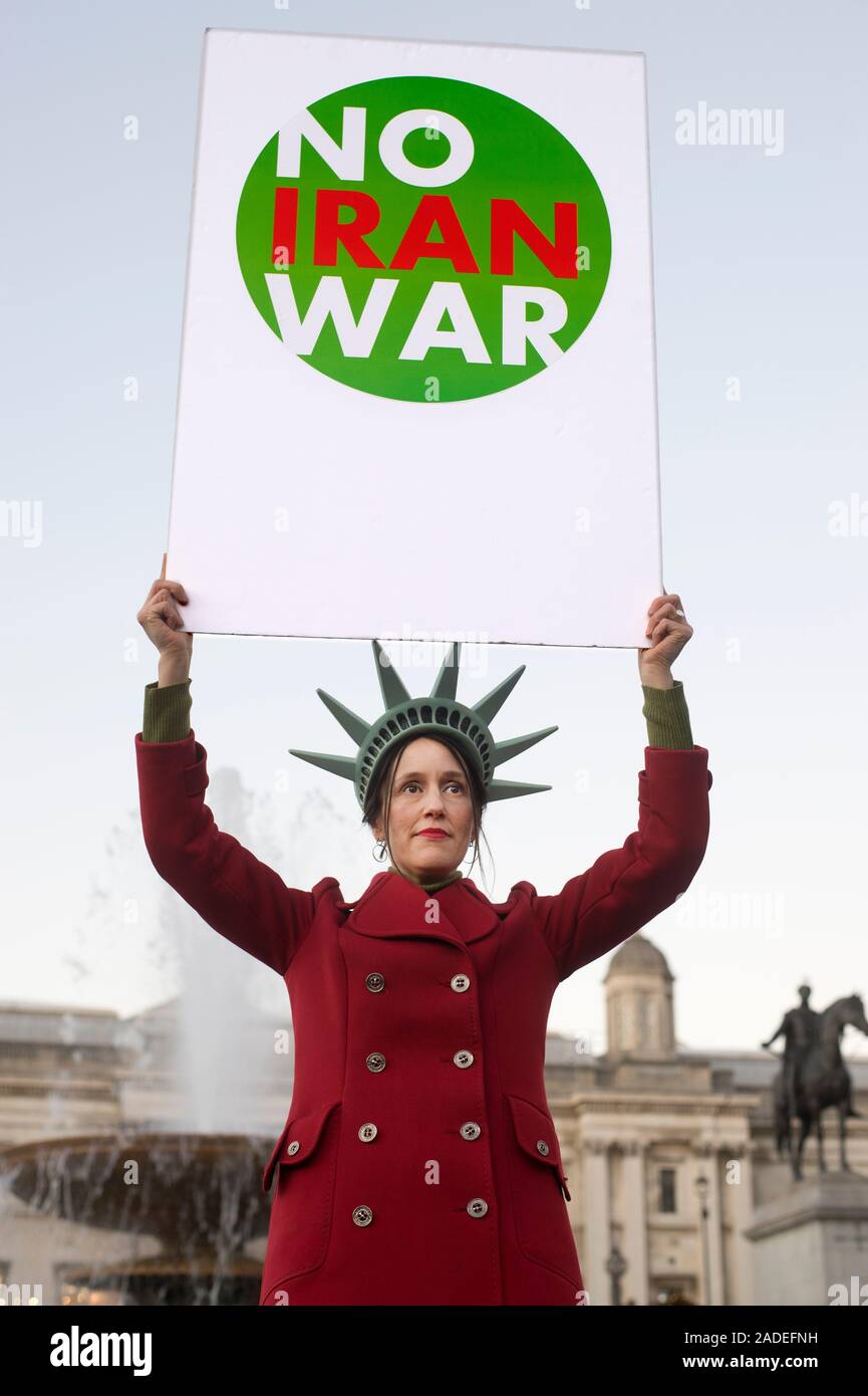 3 décembre 2019 Trafalgar Square. Manifestation anti Trump. Une femme portant une robe de la tête de la Statue de la liberté est titulaire d'un panneau disant 'Non' de la guerre de l'Iran Banque D'Images