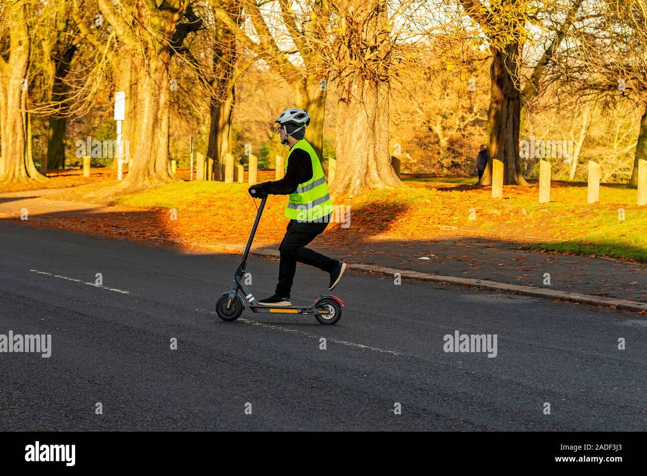 Un homme sur un scooter électrique-aider crossing Park Avenue South, Northampton, Royaume-Uni. Banque D'Images