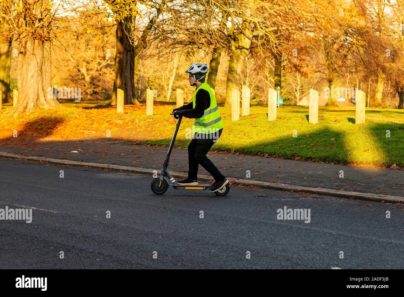 Un homme sur un scooter électrique-aider crossing Park Avenue South, Northampton, Royaume-Uni. Banque D'Images