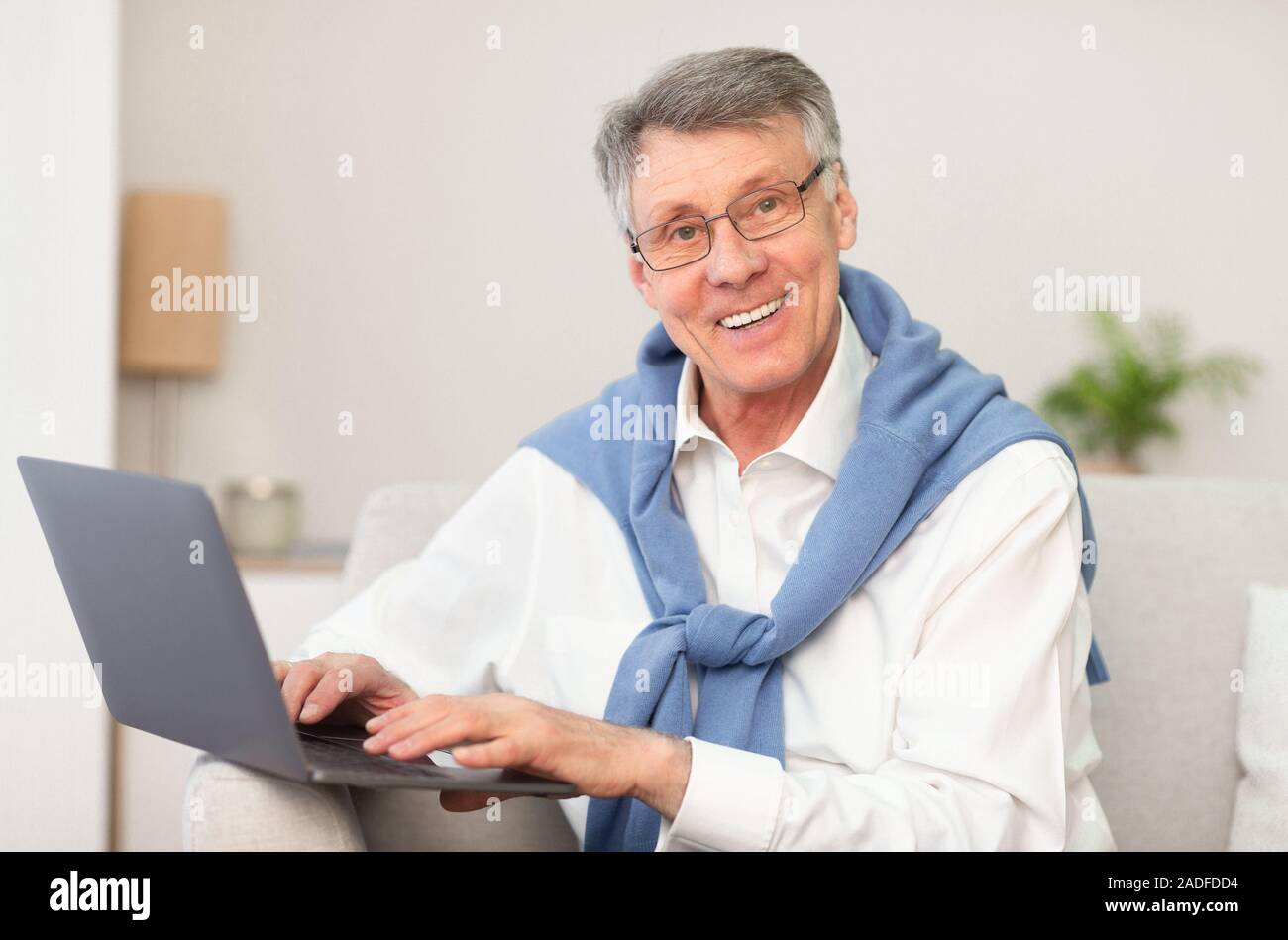 Man working on Laptop Sitting on Sofa At Home Banque D'Images