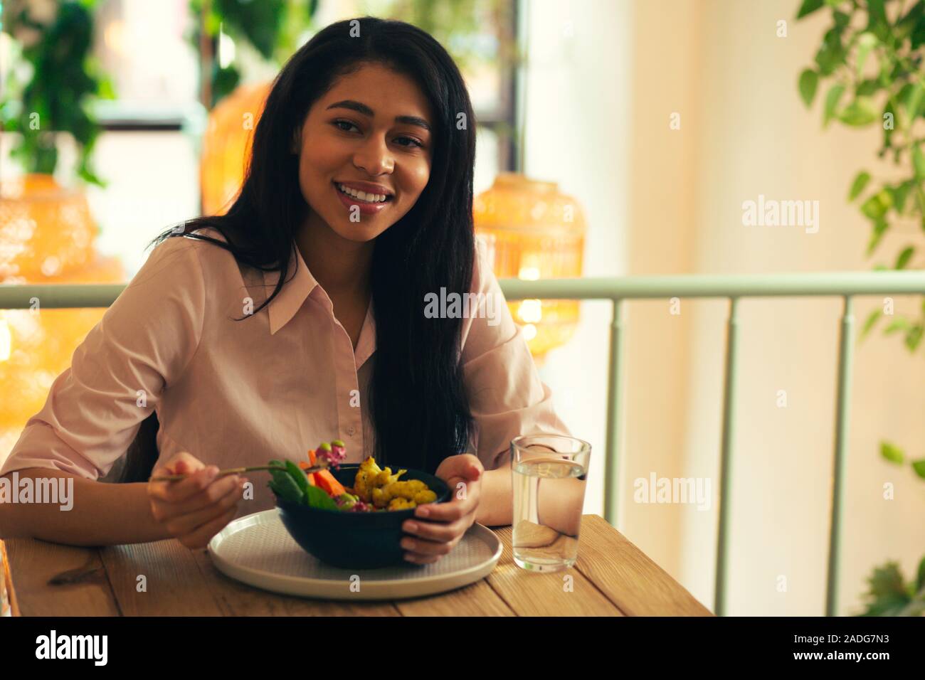 Ravie dame souriant tout en déjeunant seul Banque D'Images