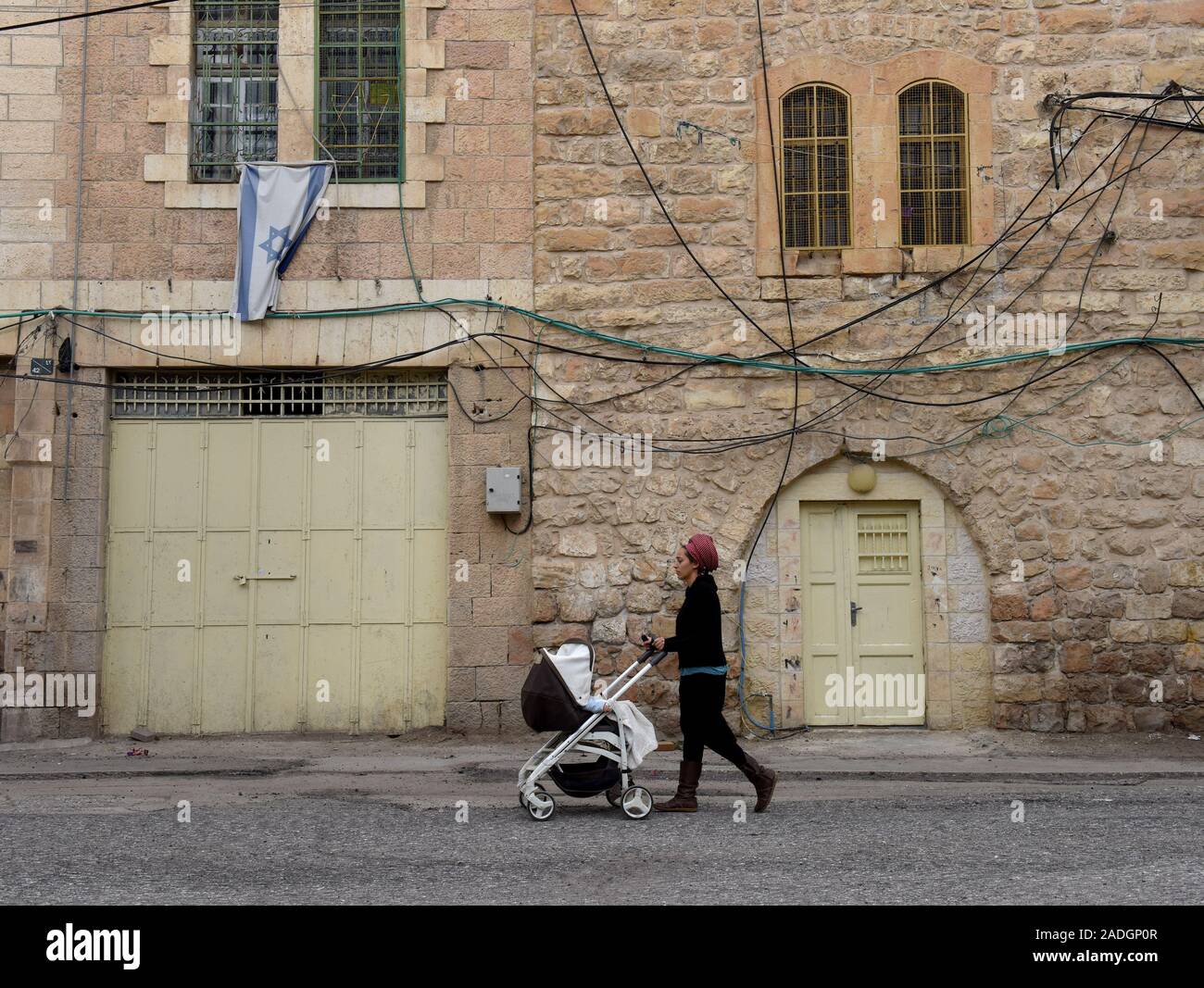 Un colon juif pousse son bébé sous un drapeau israélien, suspendu à une maison palestinienne, sur la rue Shuhada près du Tombeau des Patriarches, ou de la mosquée, dans la ville divisée de Hébron, en Cisjordanie, le Mercredi, Décembre 4, 2019. Le Ministre israélien de la Défense, Naftali Bennett a ordonné aux fonctionnaires de commencer à planifier une nouvelle colonie juive au coeur d'Hébron, dont les responsables palestiniens dire, c'est la suite de Le président américain Donald Trump a décidé de légitimer les colonies. Photo par Debbie Hill/UPI Banque D'Images