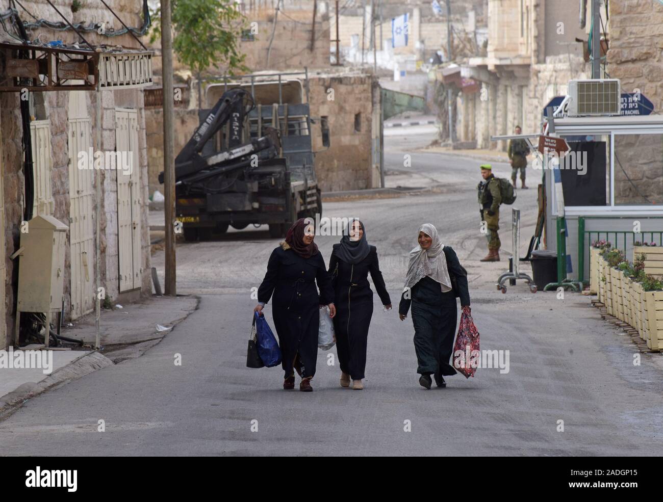 Un soldat israélien surveille les femmes palestiniennes à pied sur la rue Shuhada près du Tombeau des Patriarches, ou de la mosquée, dans la ville divisée de Hébron, en Cisjordanie, le Mercredi, Décembre 4, 2019. Le Ministre israélien de la Défense, Naftali Bennett a ordonné aux fonctionnaires de commencer à planifier une nouvelle colonie juive au coeur d'Hébron, dont les responsables palestiniens dire, c'est la suite de Le président américain Donald Trump a décidé de légitimer les colonies. Photo par Debbie Hill/UPI Banque D'Images