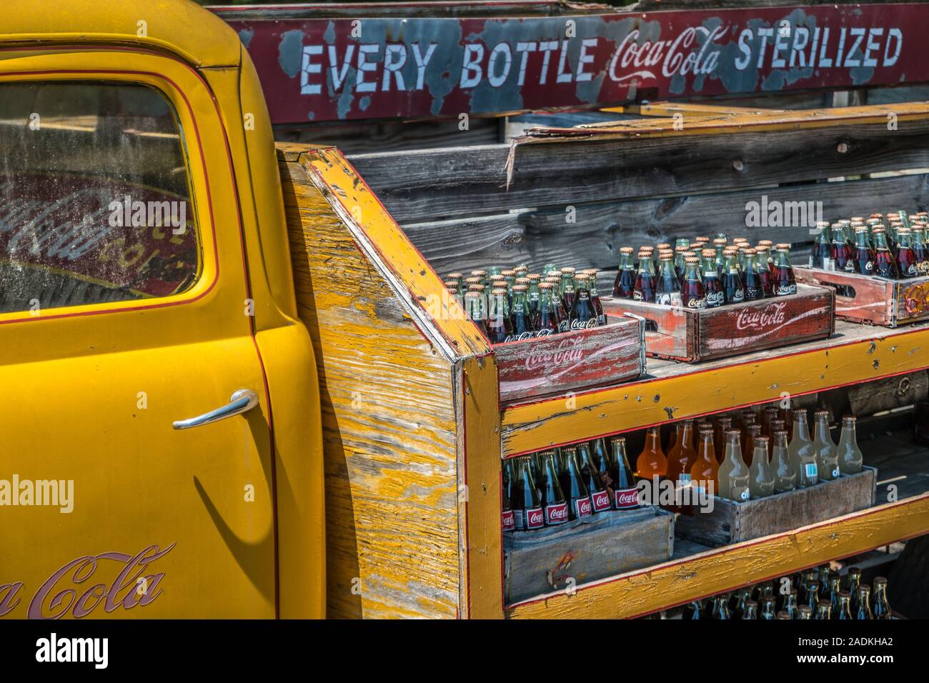 Vue partielle d'un vieux camion de livraison Coca-Cola vintage avec des bouteilles de coca alignées dans une caisse en bois empilés sur des étagères de résisté à l'extérieur assis Banque D'Images
