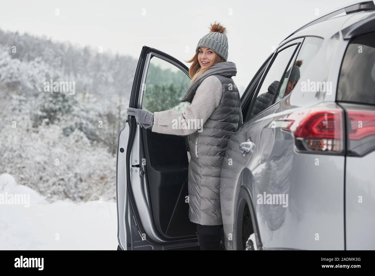 Femme marche hors de la voiture moderne pour avoir une promenade dans la belle forêt d'hiver Banque D'Images