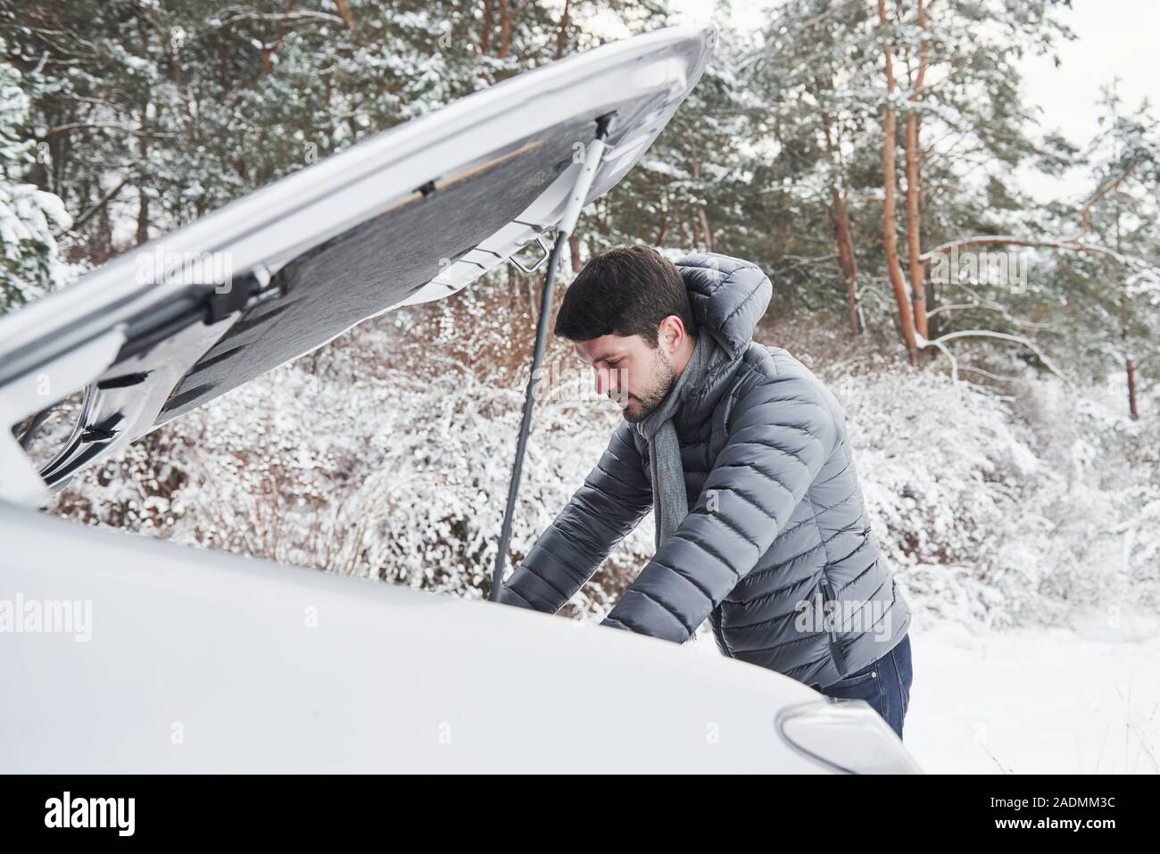 Guy coincé dans la forêt d'hiver parce que sa voiture a des problèmes. Essaie de réparer l'automobile Banque D'Images