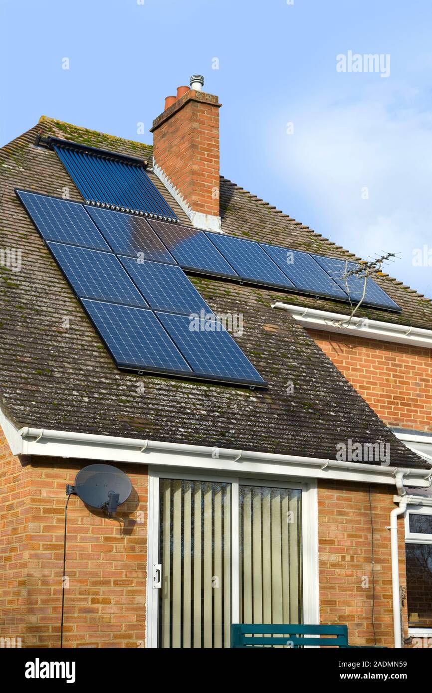 Les systèmes d'énergie solaire. Les tubes de chauffage solaire (en haut) et  un éventail de modules photovoltaïques (PV) sur le toit d'une maison. Un  système de chauffage d'eau solaire passif com Photo