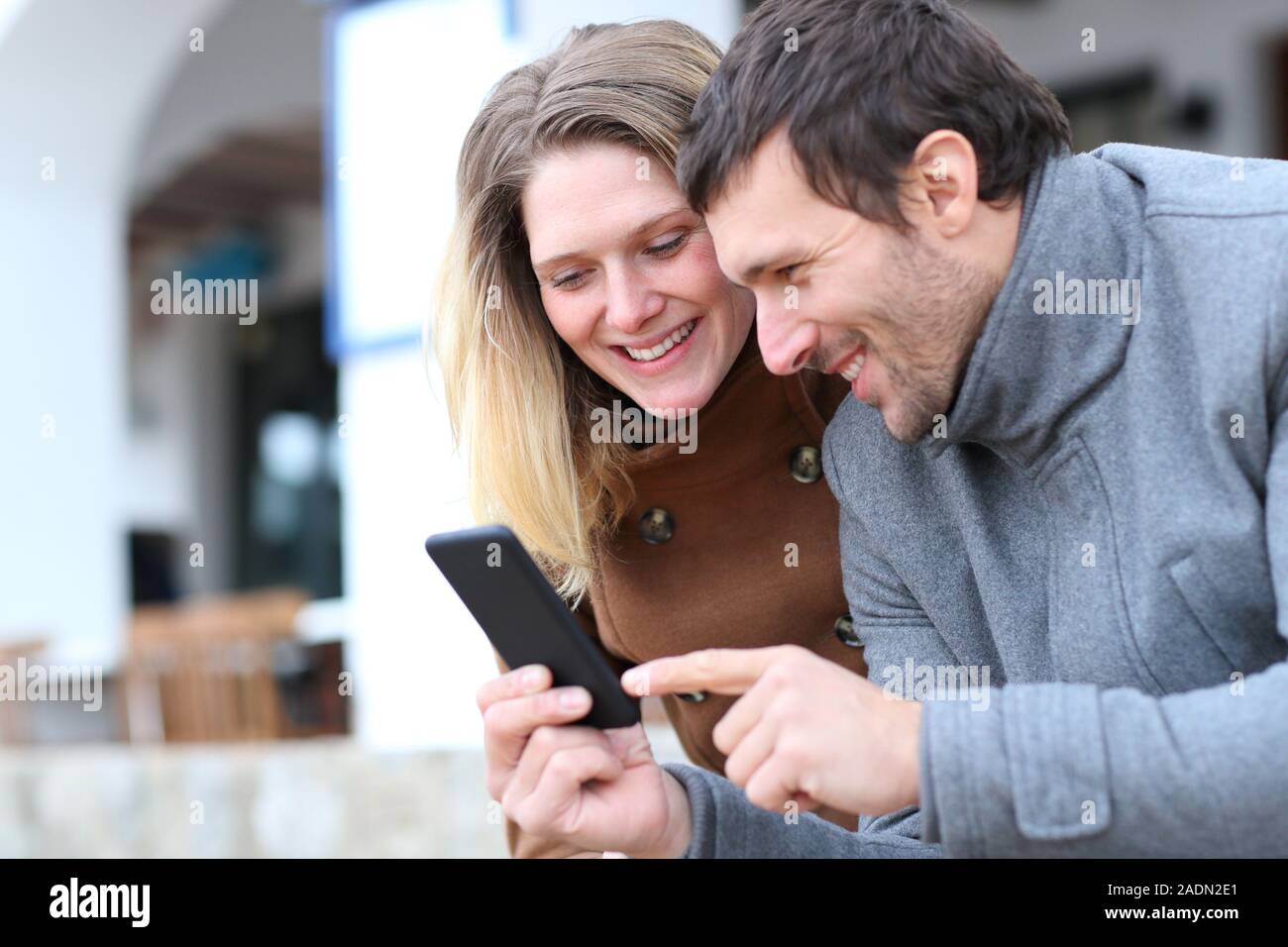 Heureux couple d'adultes contrôle smart phone en ligne contenu dans la rue en hiver Banque D'Images