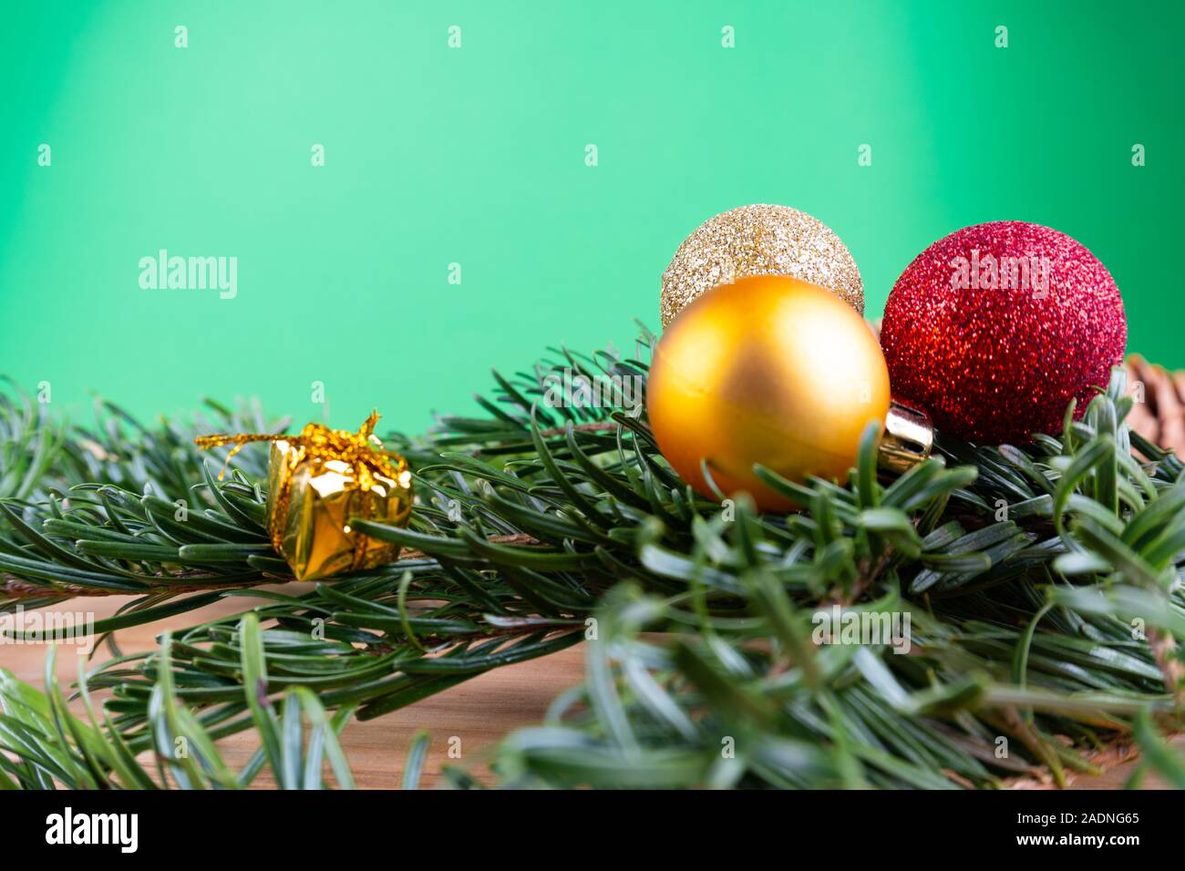 Branches de sapin vert avec des ornements de Noël (boules de Noël, des cannes de bonbon, présente) sur une table en bois devant un fond vert avec des savs copie Banque D'Images