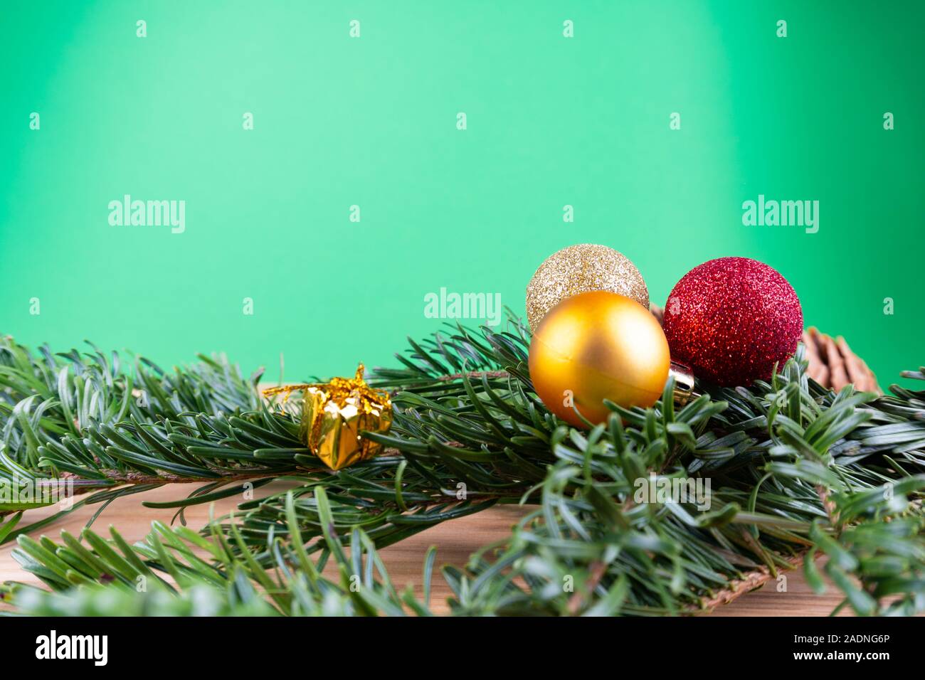 Branches de sapin vert avec des ornements de Noël (boules de Noël, des cannes de bonbon, présente) sur une table en bois devant un fond vert avec des savs copie Banque D'Images