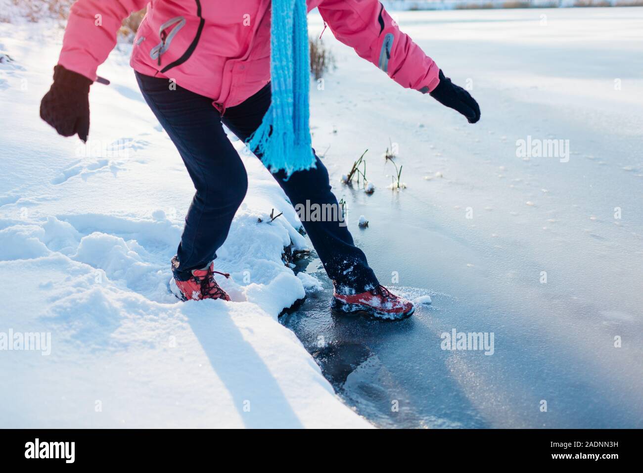 Une fine couche de glace dangereuses. Femme prend des risques pour l'étape sur la surface de la rivière gelés en hiver. Attention, l'eau insalubre, drop possibilité Banque D'Images