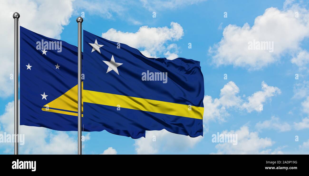 Les Tokélaou et de brandir le drapeau de Curaçao dans le vent contre ciel bleu nuageux blanc ensemble. Concept de diplomatie, de relations internationales. Banque D'Images