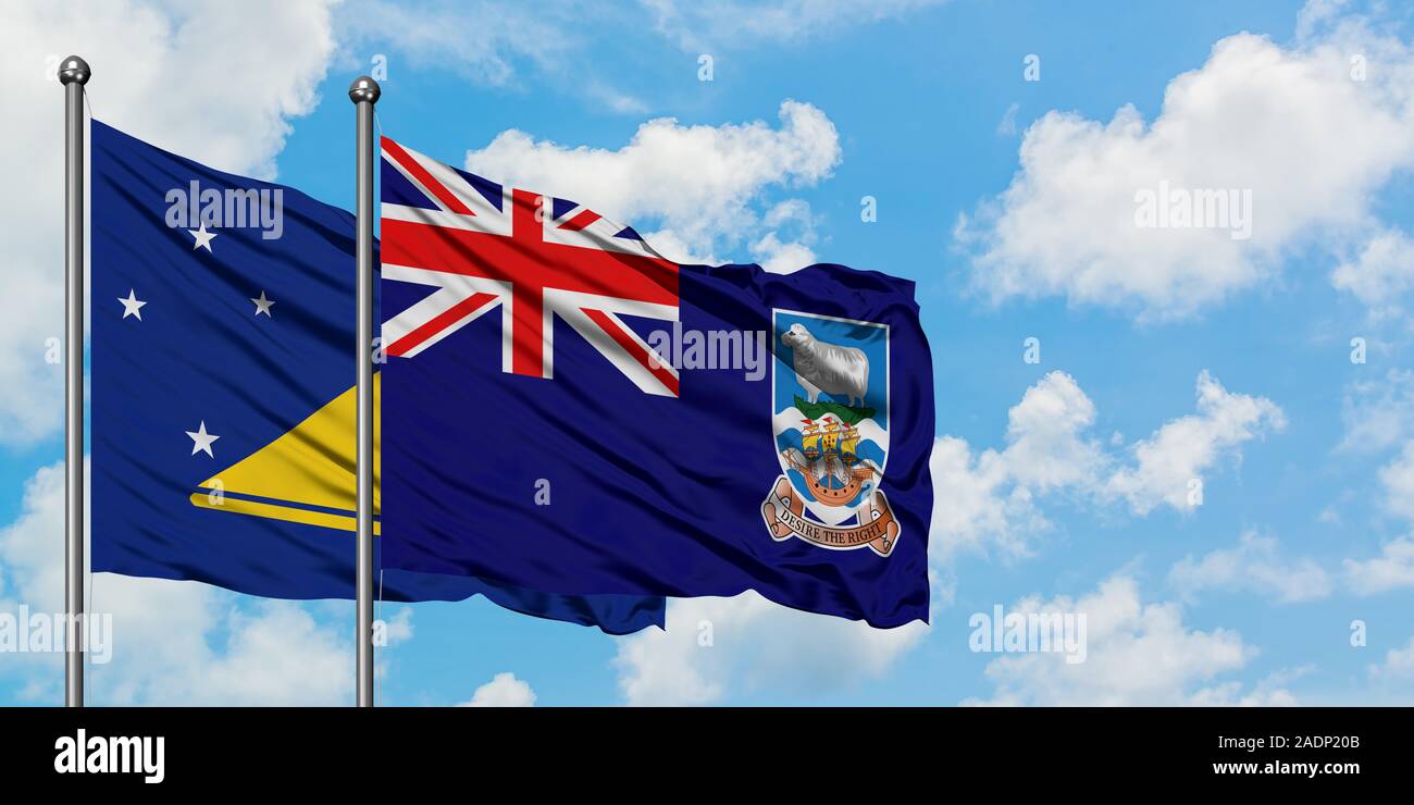 Les Tokélaou et de brandir le drapeau des Îles Falkland dans le vent contre ciel bleu nuageux blanc ensemble. Concept de diplomatie, de relations internationales. Banque D'Images