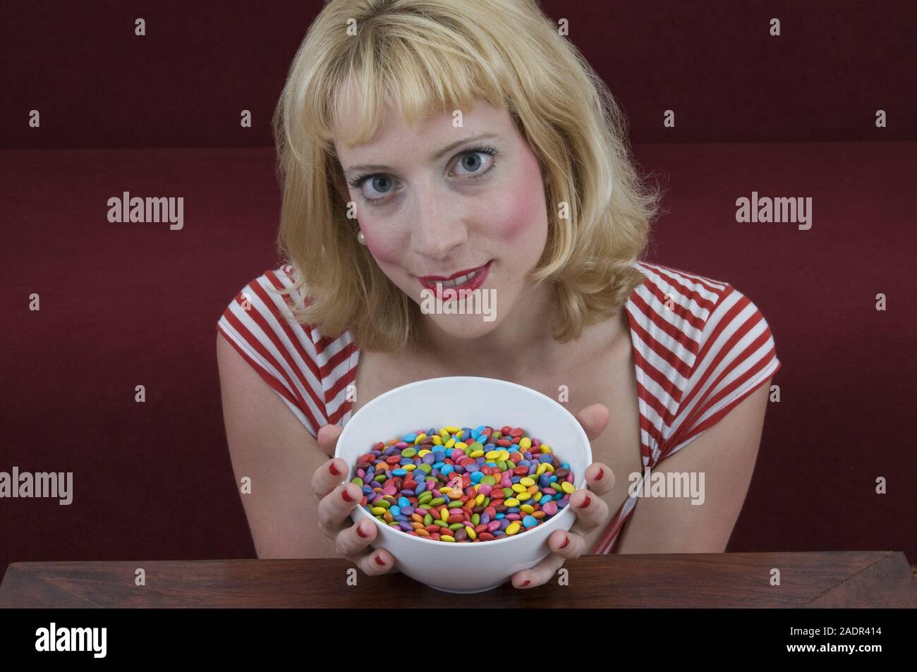 Junge Frau vor einer Schale mit Schokolinsen - Jeune femme à l'avant de la cuvette avec les lentilles au chocolat Banque D'Images