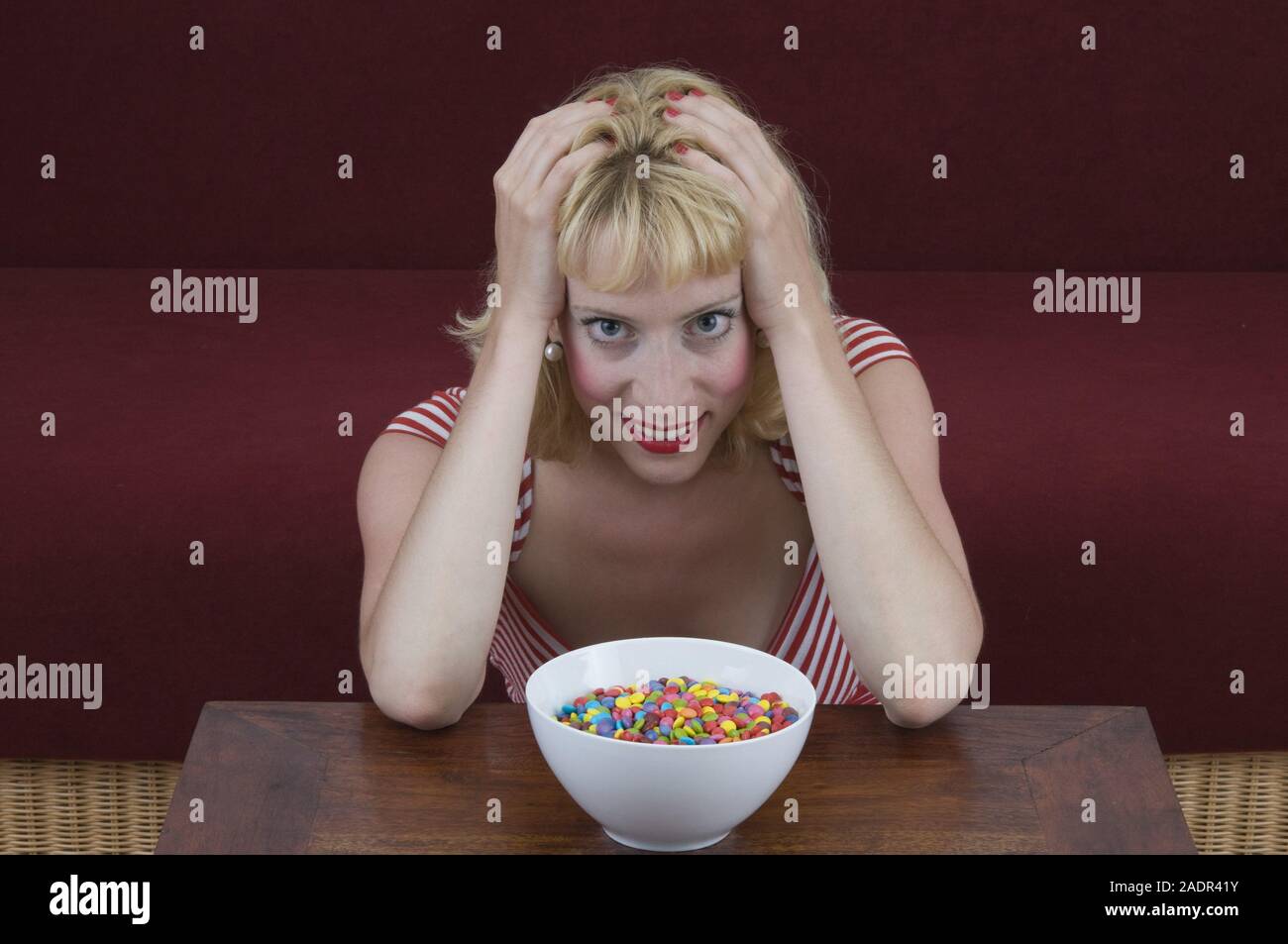 Junge Frau vor einer Schale mit Schokolinsen - Jeune femme à l'avant de la cuvette avec les lentilles au chocolat Banque D'Images