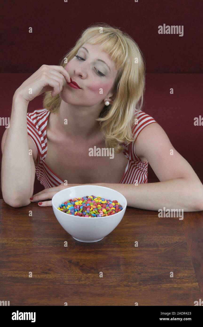 Junge Frau vor einer Schale mit Schokolinsen - Jeune femme à l'avant de la cuvette avec les lentilles au chocolat Banque D'Images