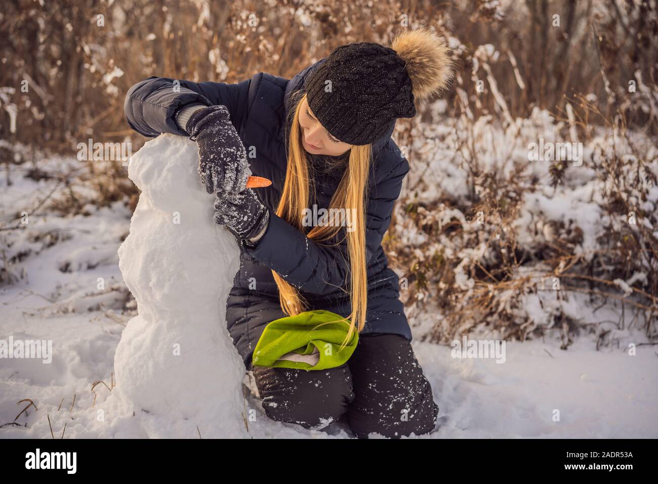 Jeune femme rouler en boule géante pour faire snowman Banque D'Images