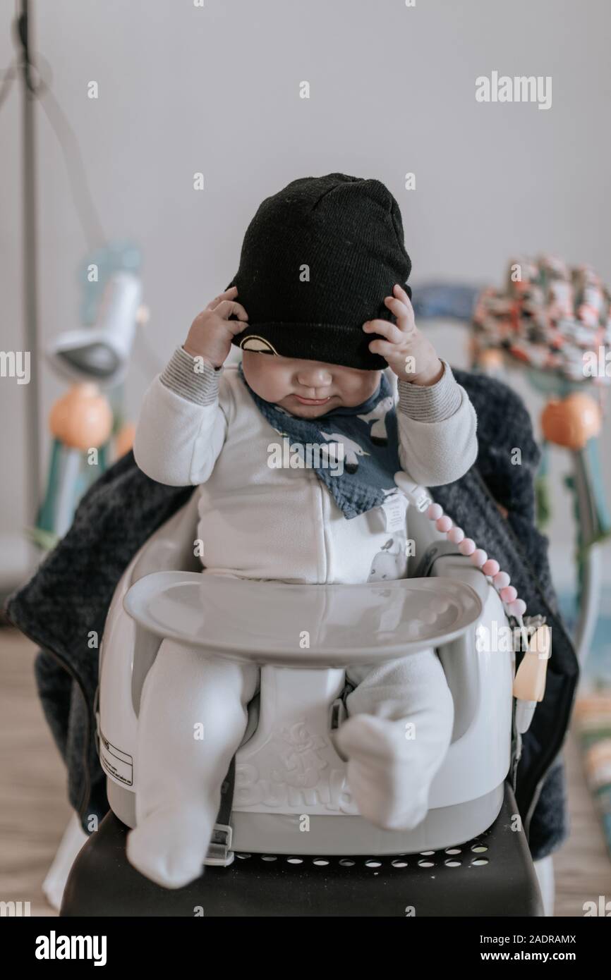 Asian baby boy sitting et jouer avec chapeau à la maison. Enfant est de 6 mois. Banque D'Images