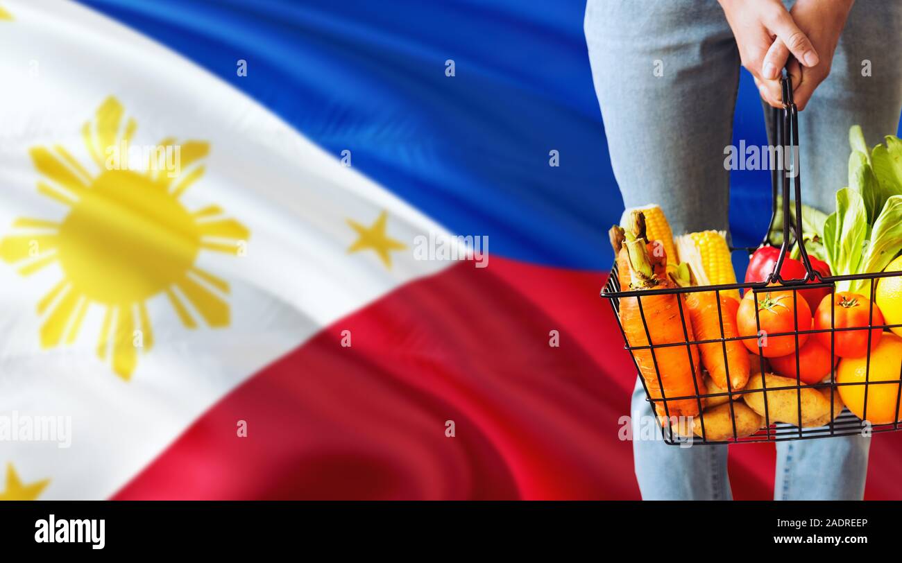 Woman is holding supermarché panier, Philippines waving flag background. Concept de l'économie pour les fruits et légumes. Banque D'Images