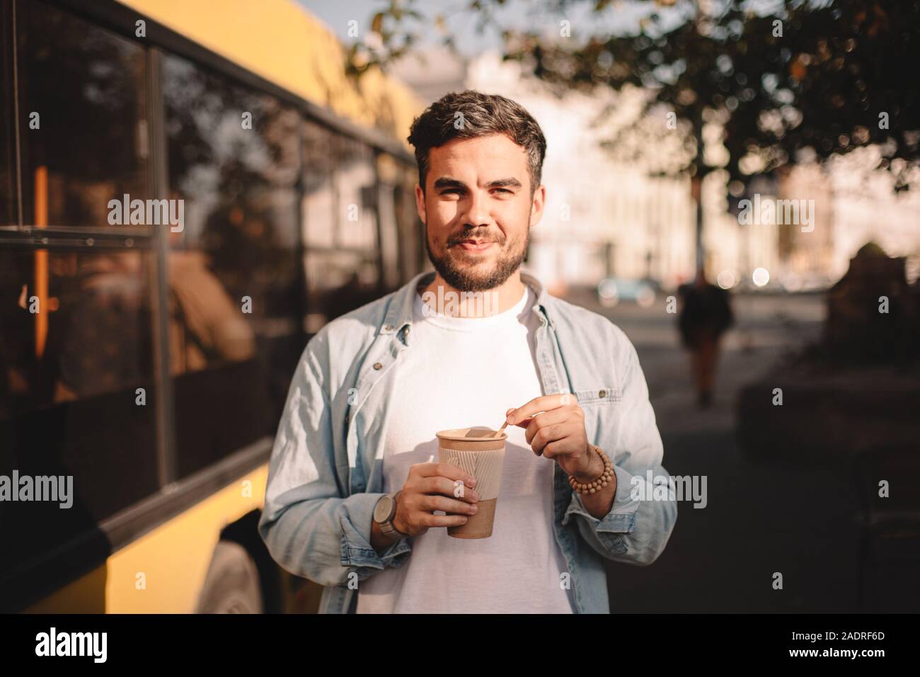 Happy man holding tasse de café tout en se tenant sur la rue en été Banque D'Images