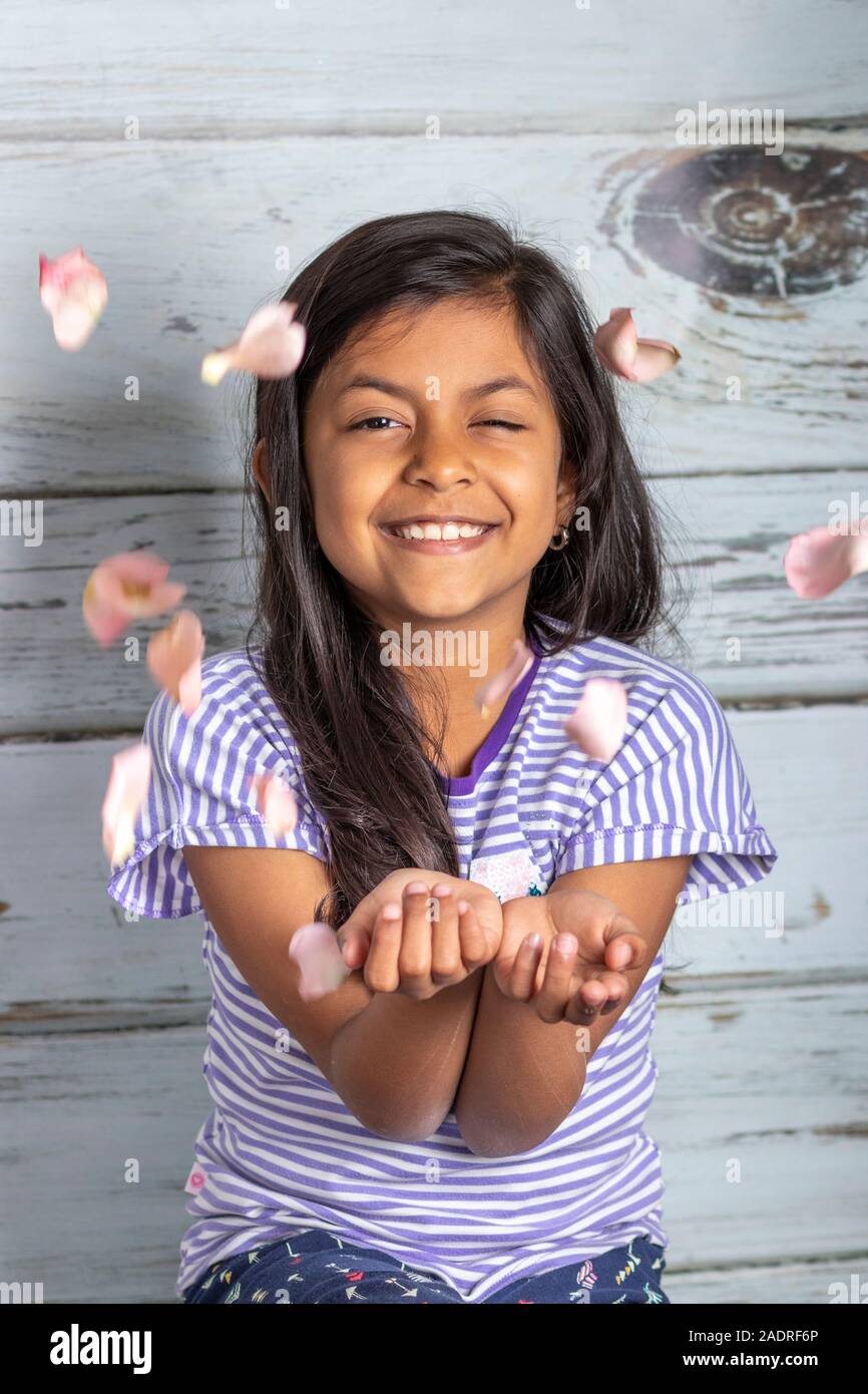 Cute brunette fille jouant avec des pétales de rose Banque D'Images