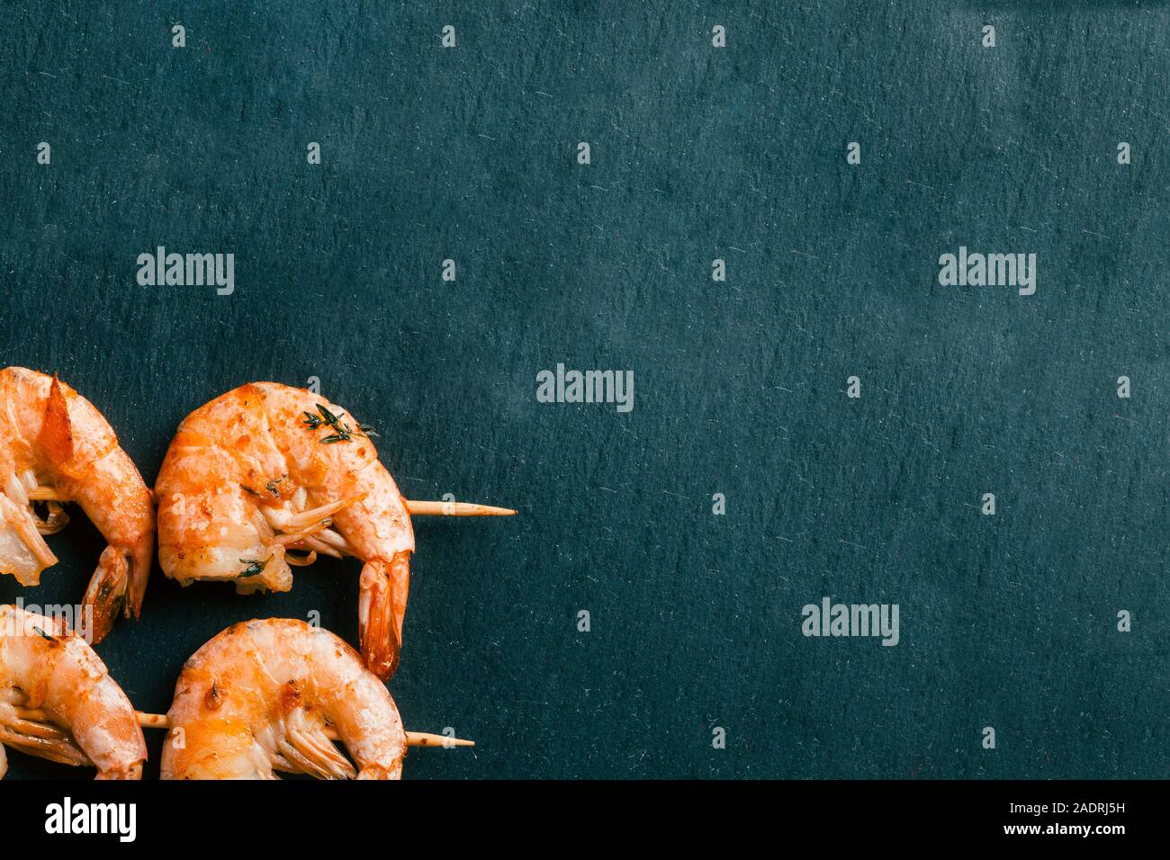 Photo horizontale de l'ardoise noire avec deux brochettes de crevettes Banque D'Images
