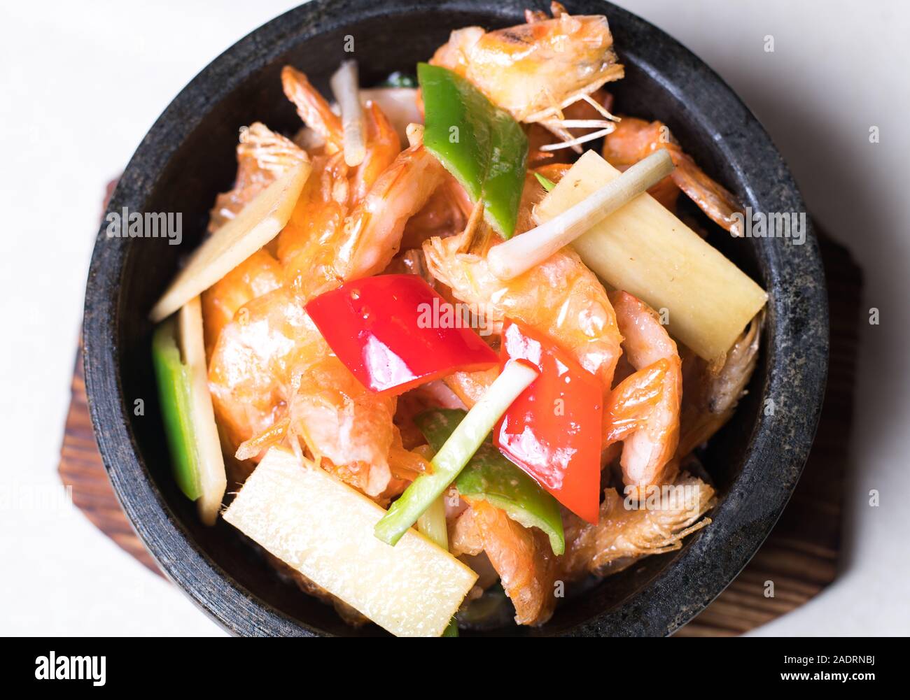 Sauté de crevettes dans un wok avec les assiettes de service dans l'arrière-plan Banque D'Images