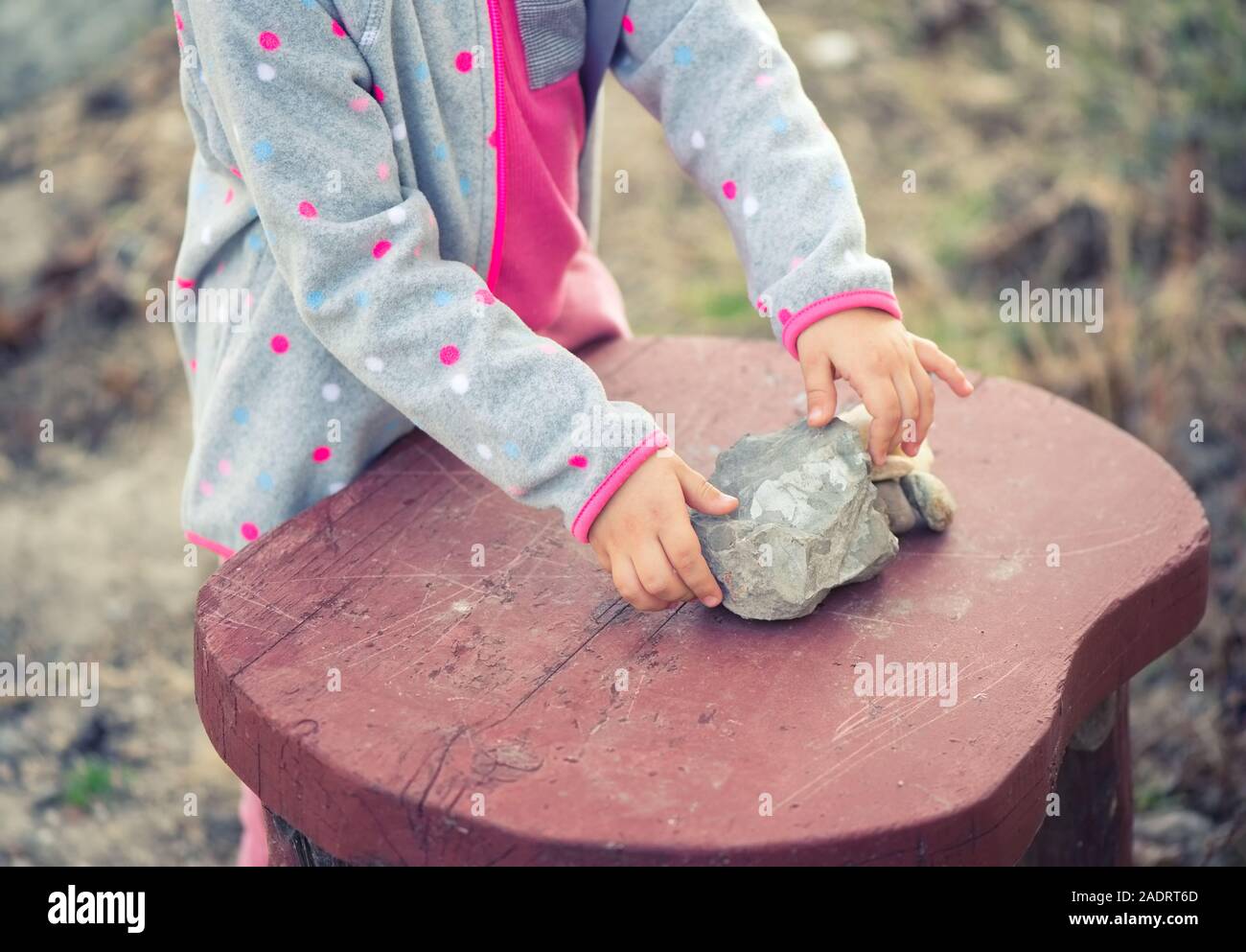 Enfant jouant avec des pierres sur une table en bois Banque D'Images