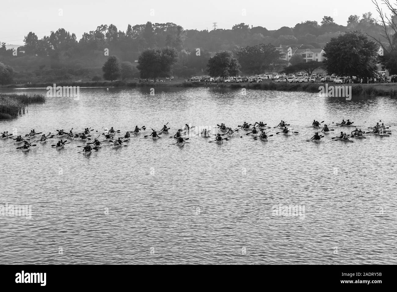 Course en canots mens doubles athlètes pagayeurs à ligne de départ sur l'eau de la rivière à l'aube des armes officielles d'attente paysage de l'arrière photo en noir et blanc. Banque D'Images
