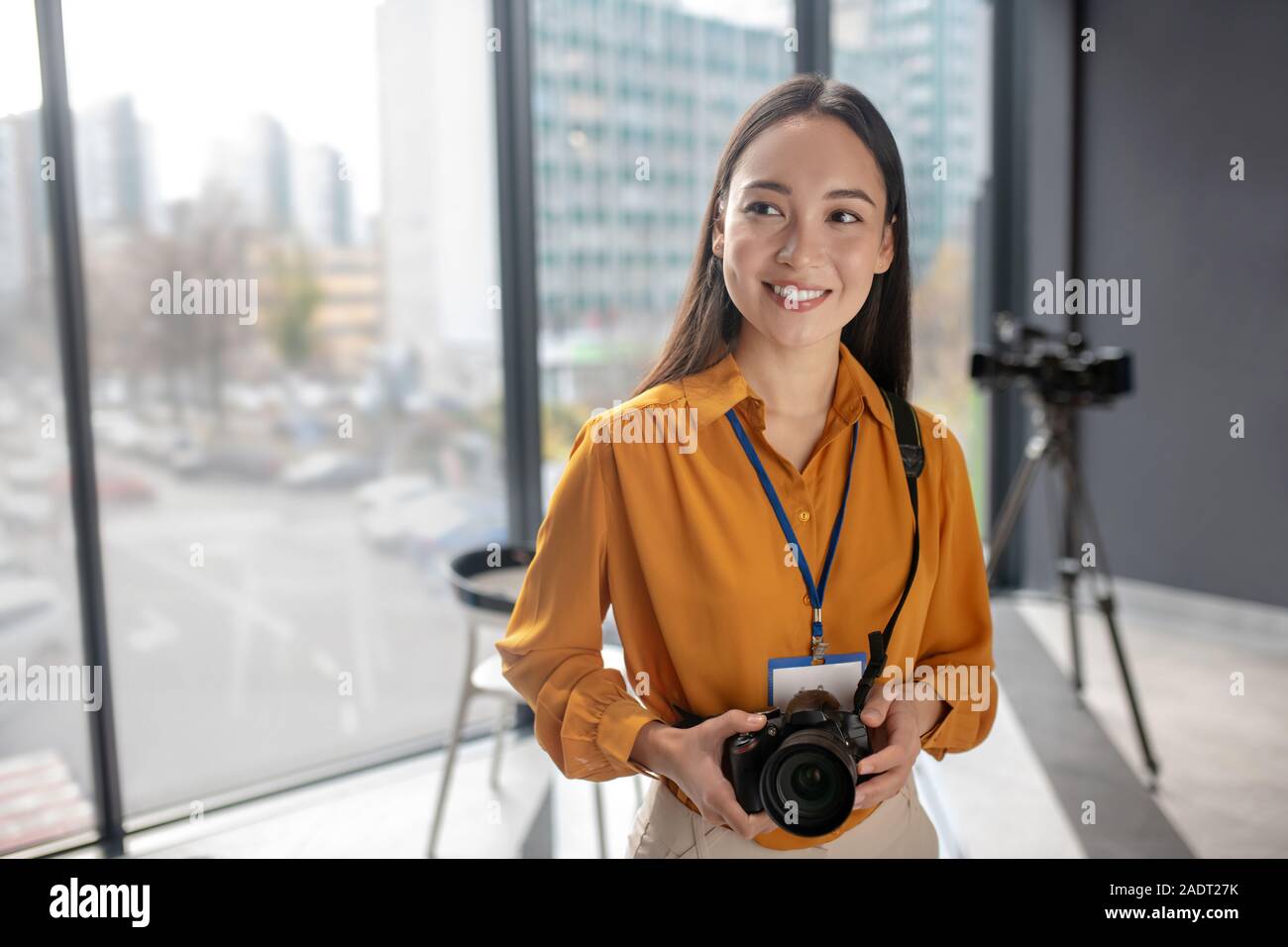 Dark-haired jeune reporter holding a camera Banque D'Images