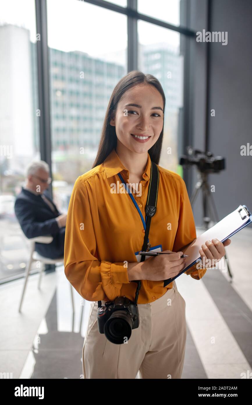 Dark-haired jeune reporter avec l'appareil photo se sentir heureux Banque D'Images