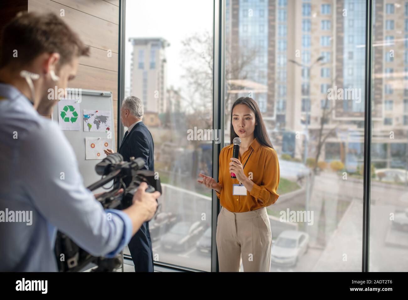 Dark-haired femme journaliste parlant à la videocamera Banque D'Images